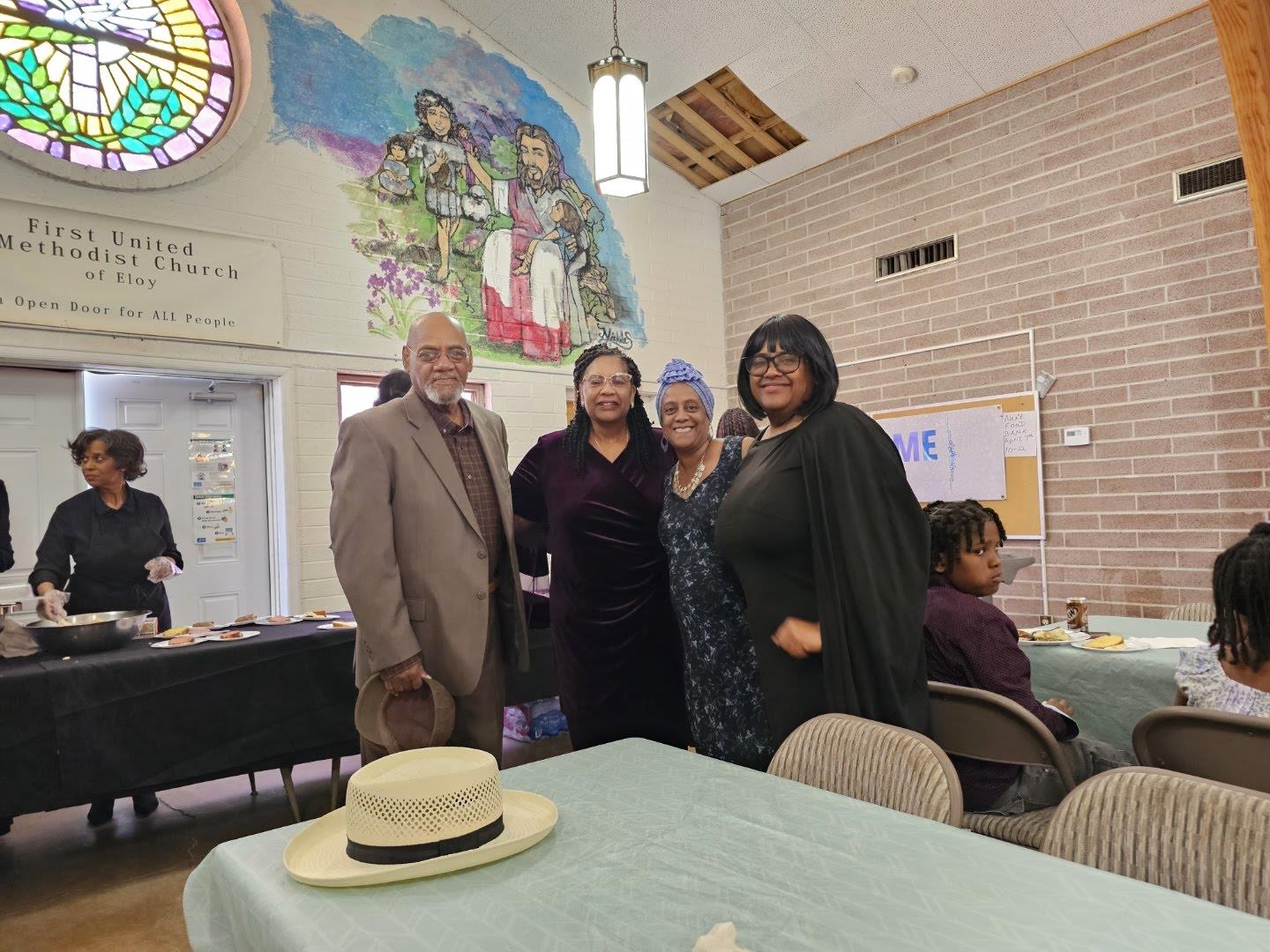 Four individuals pose together in a colorful community space during a cultural event.