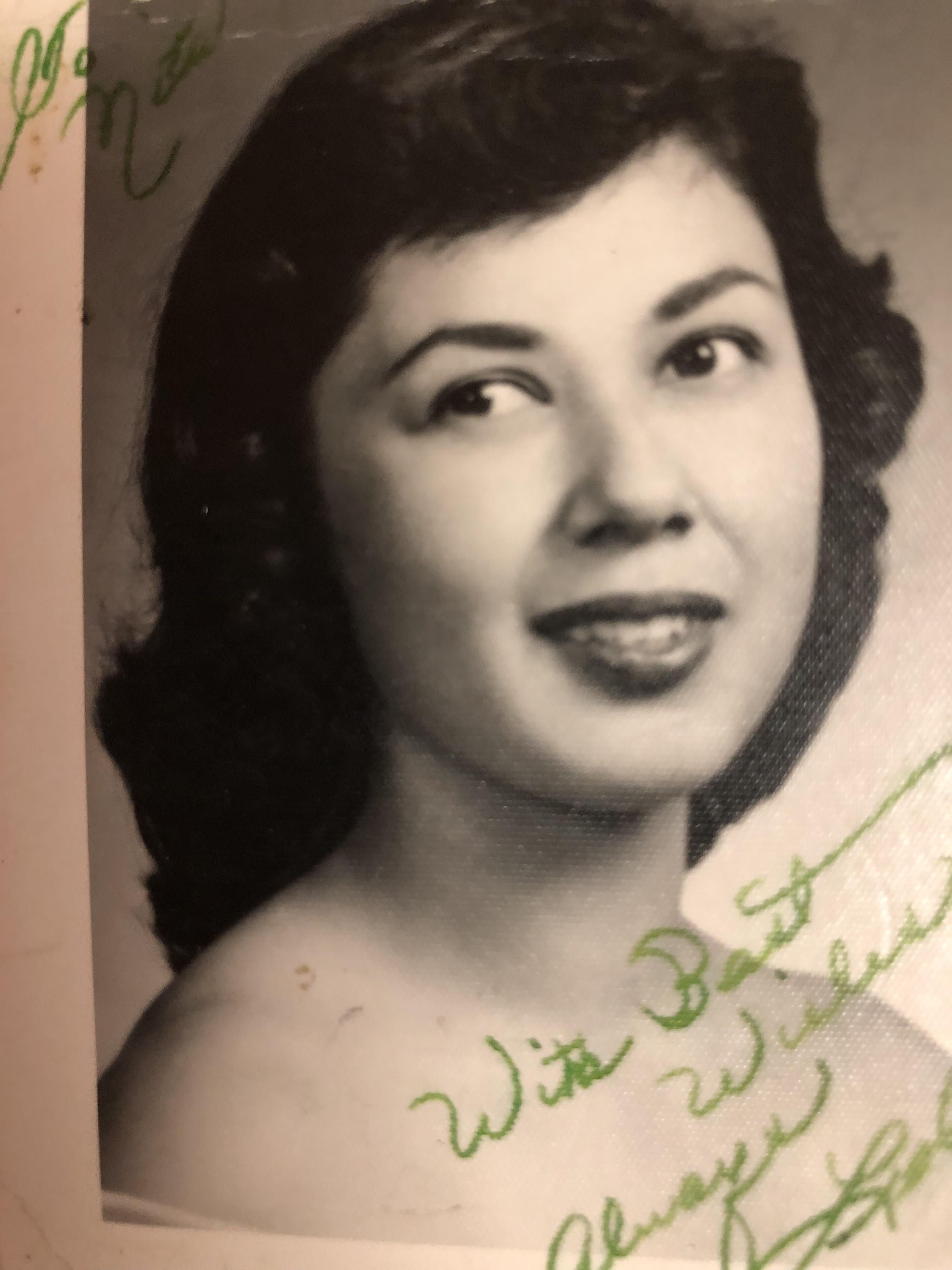 A smiling woman poses for a portrait, showcasing her wavy hair and timeless elegance.