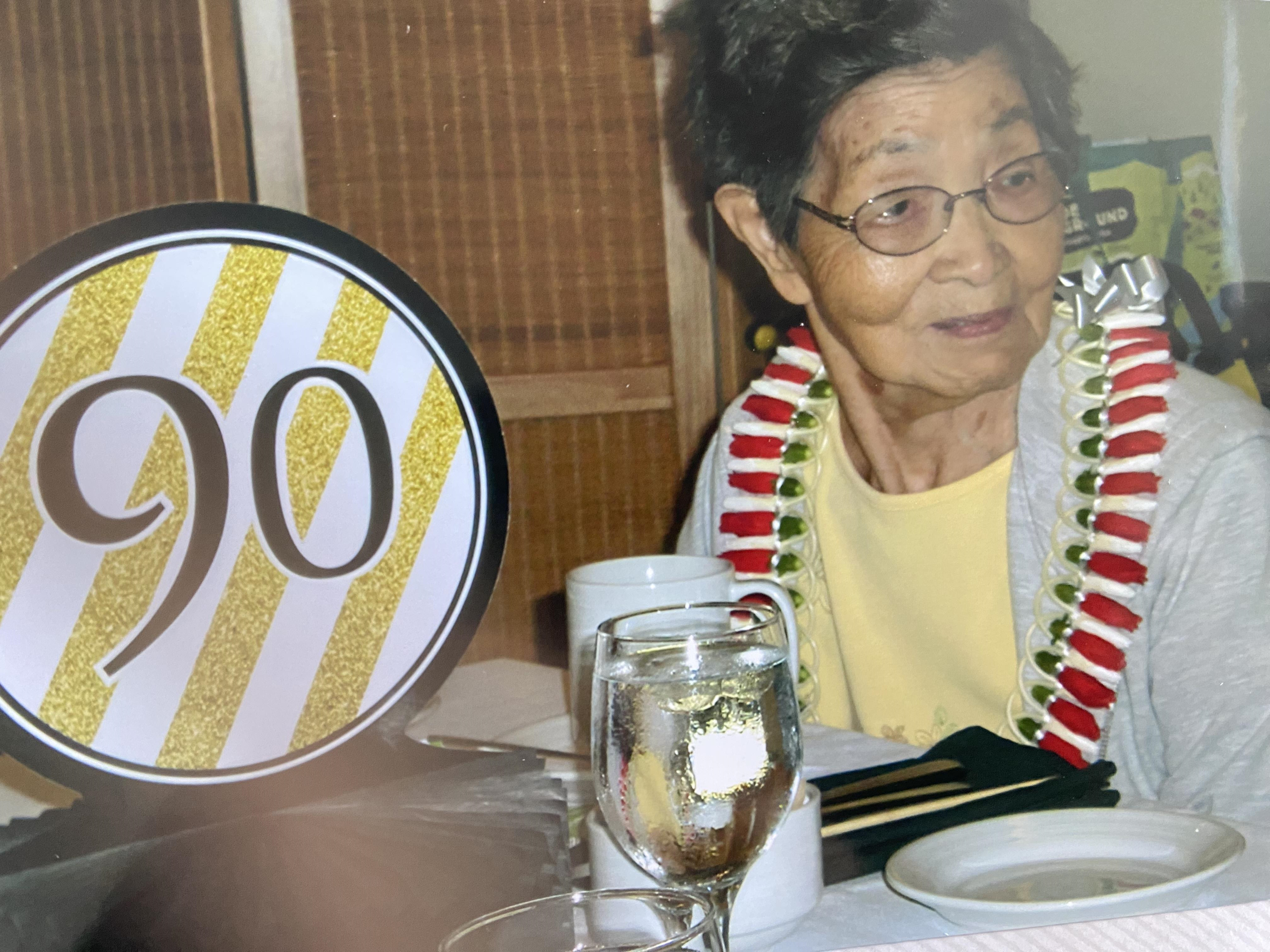 A woman beams at her birthday party, surrounded by festive décor and a special table.