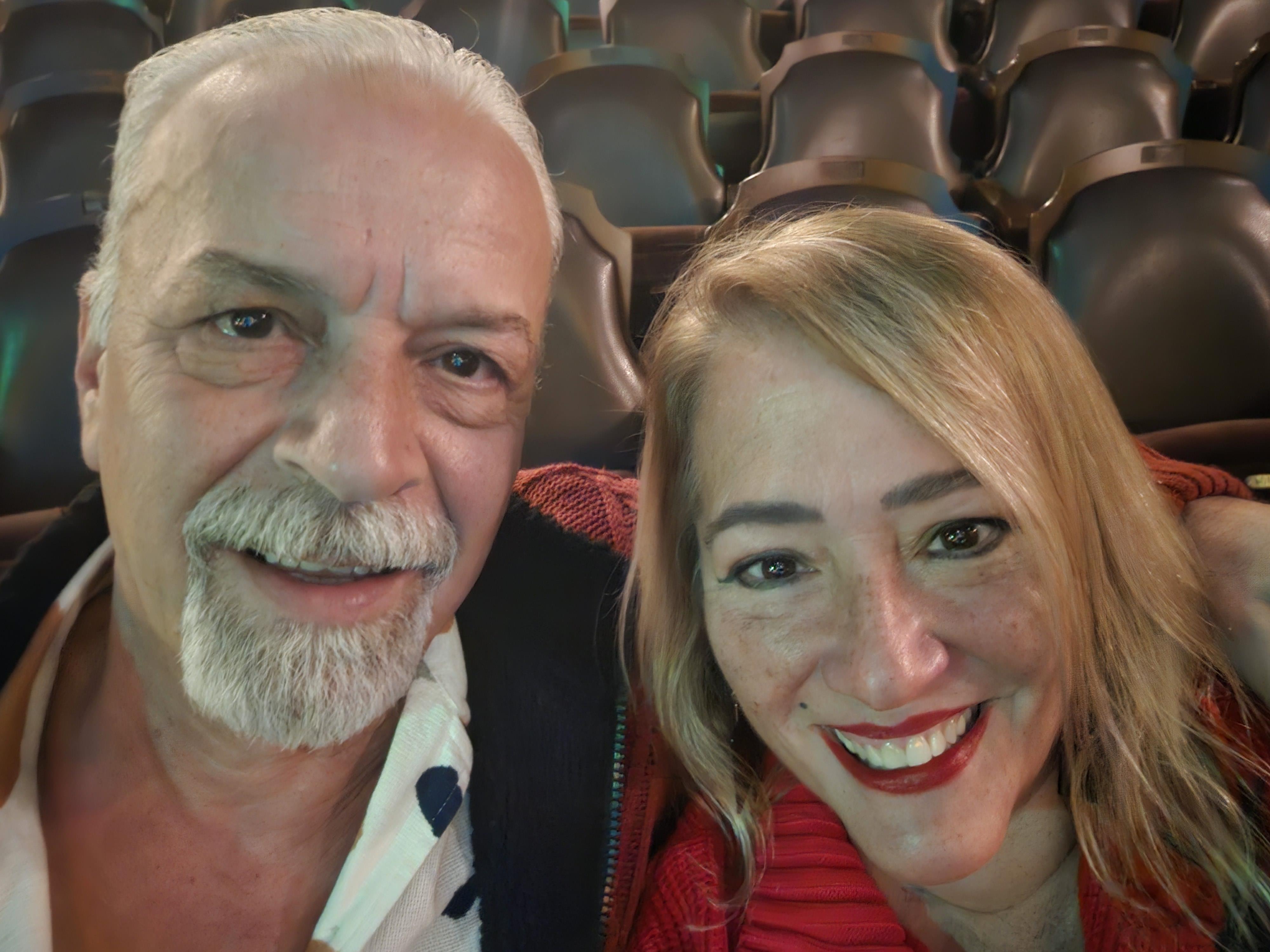 Two people smile happily together while enjoying an event in a warm and inviting theater.