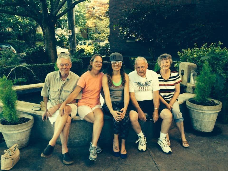 Friends gather together, smiling and relaxing on a stone bench under the sun in a park.