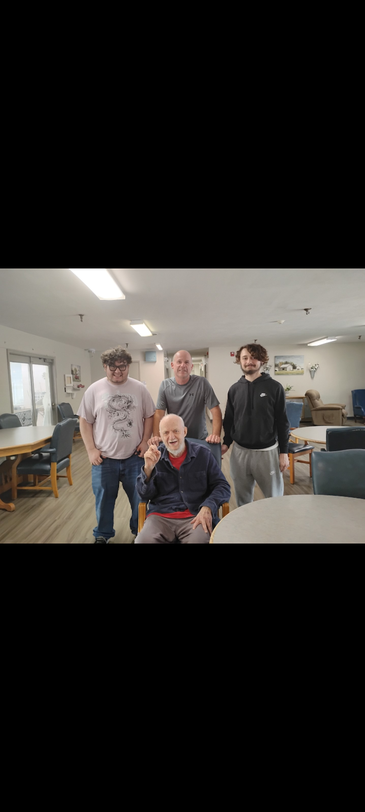 Four people are gathered together in a sunny communal area, smiling and enjoying their time.