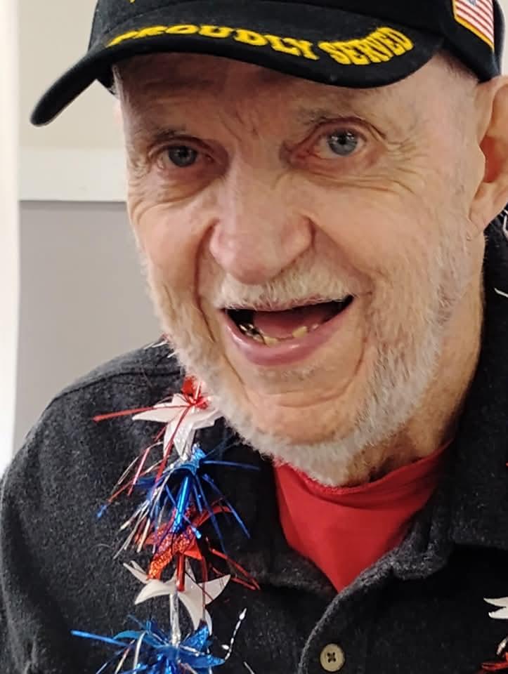 An elderly man smiles widely while engaging in a lively patriotic celebration with decorations.