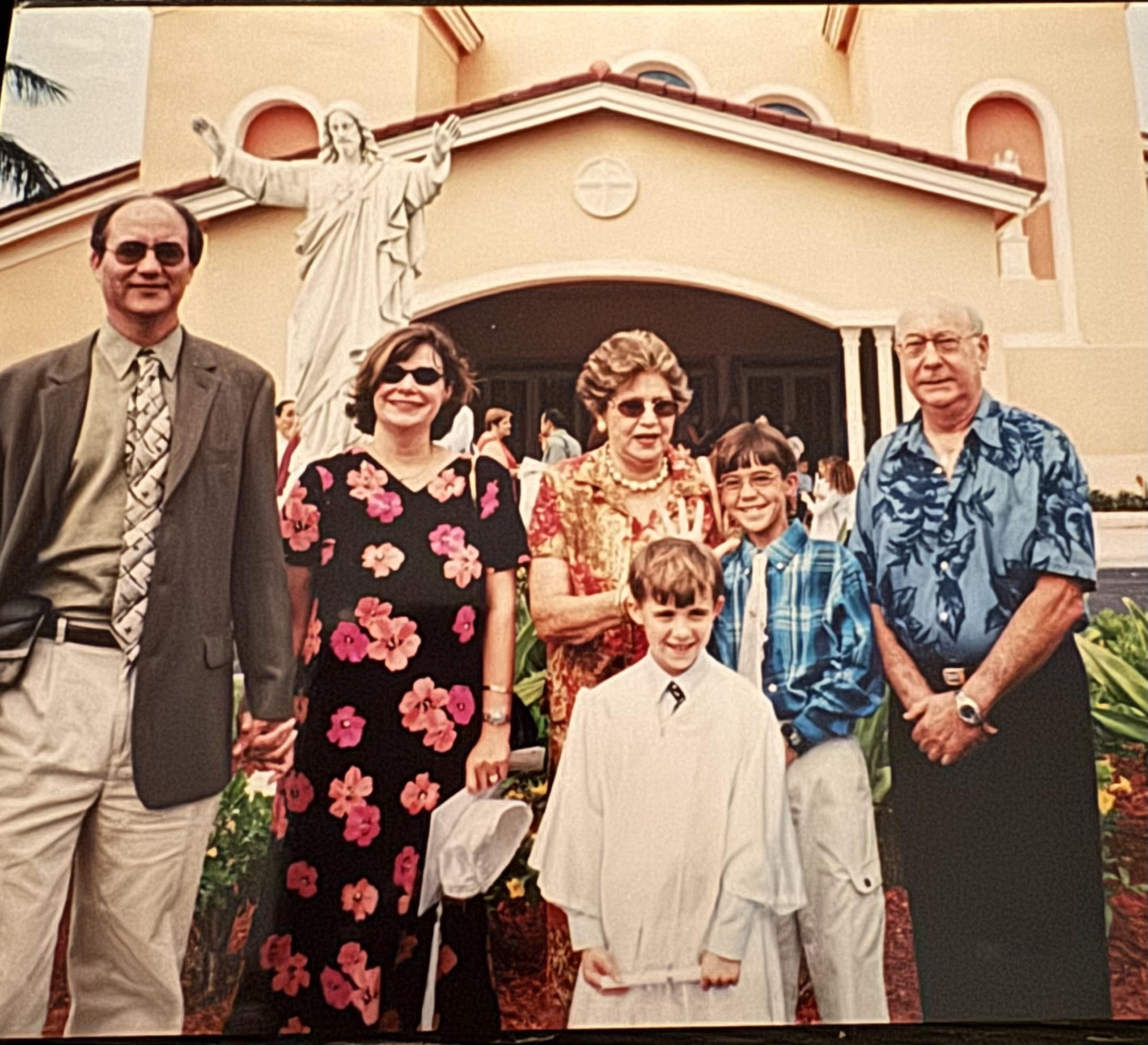 Group of family members gathers at a church, dressed in colorful outfits, smiling joyfully together.