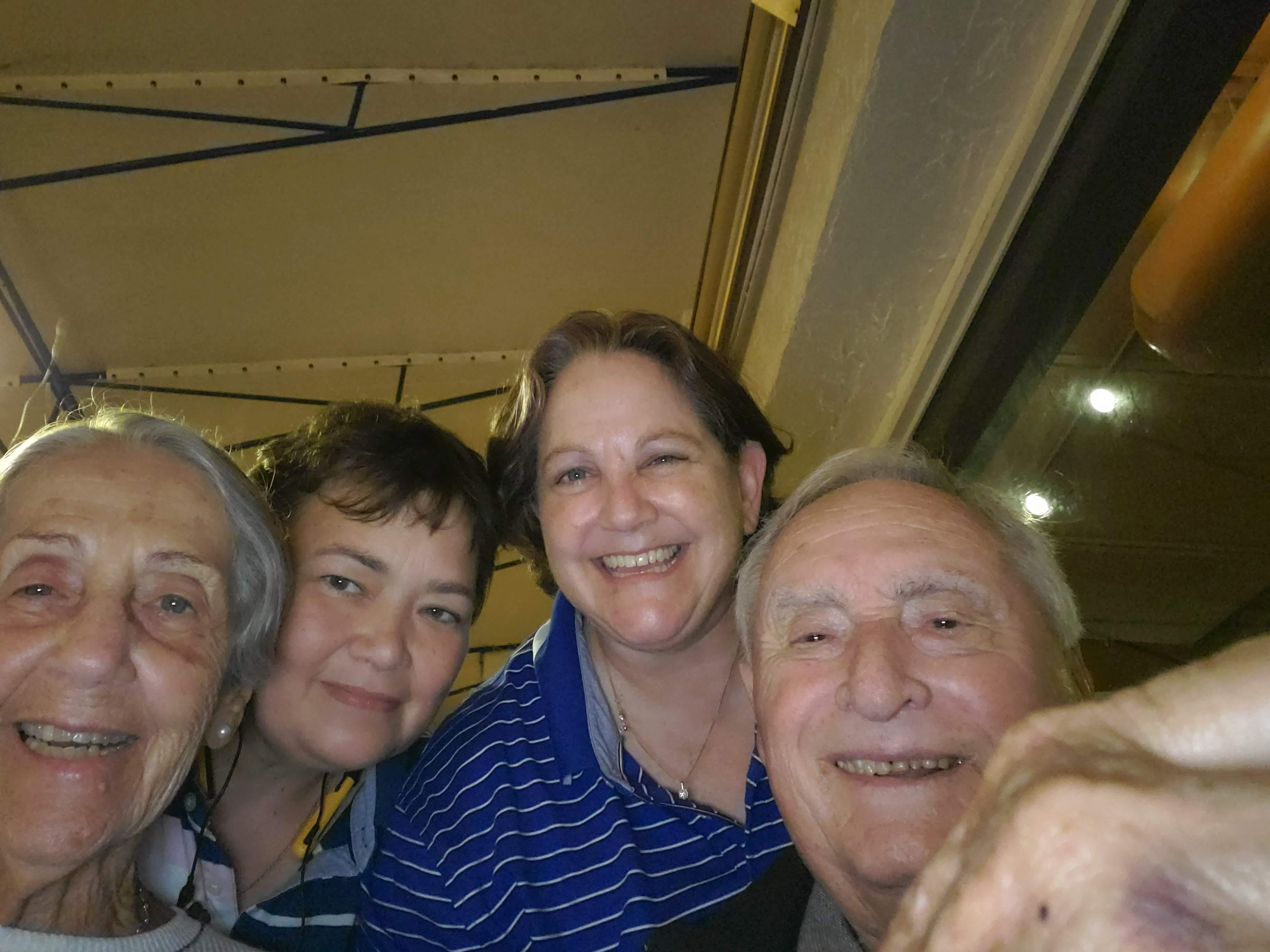 A group of five friends poses happily for a photo at a cozy gathering during evening hours.