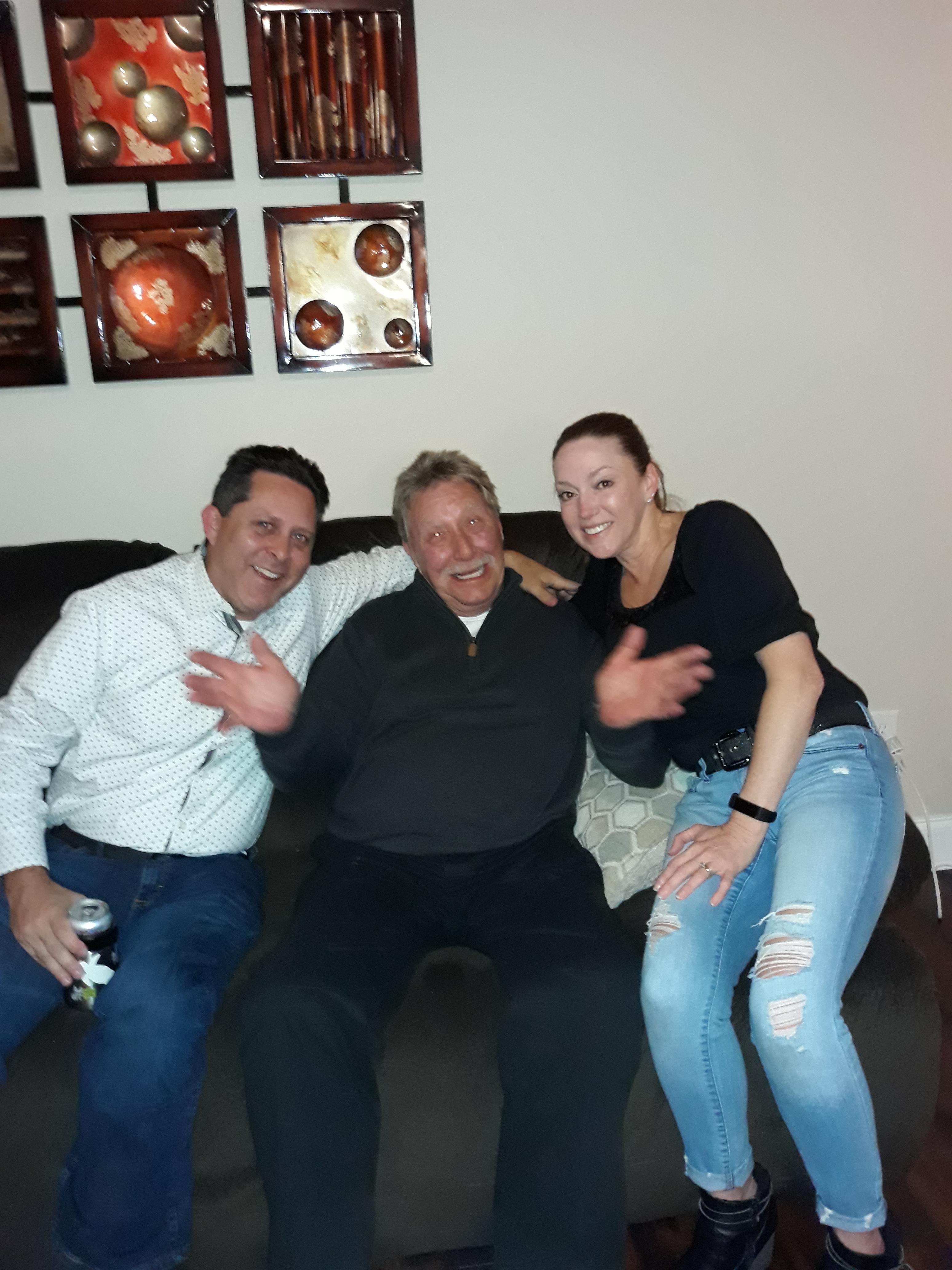 Three friends share laughs while sitting on a couch in a warm, inviting living room.