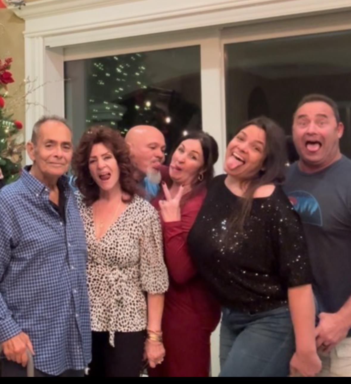 Group of family members enjoy festive fun, posing happily in a decorated living room.