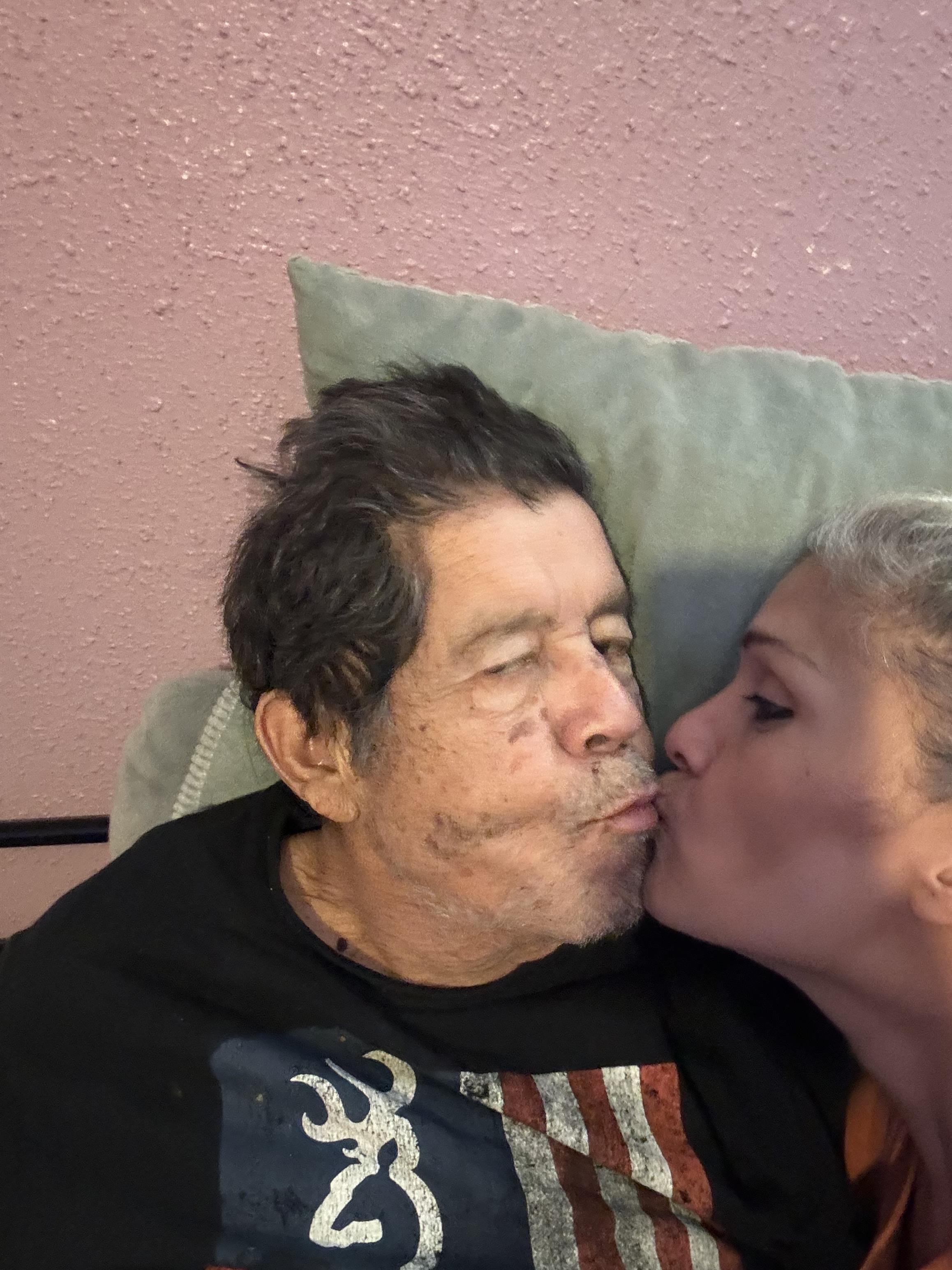 A man and woman are close together, sharing a tender kiss while relaxing on a couch.