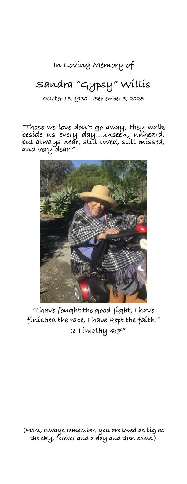 An elderly woman sits on a mobility scooter in a garden, enjoying the sunny weather and flowers.