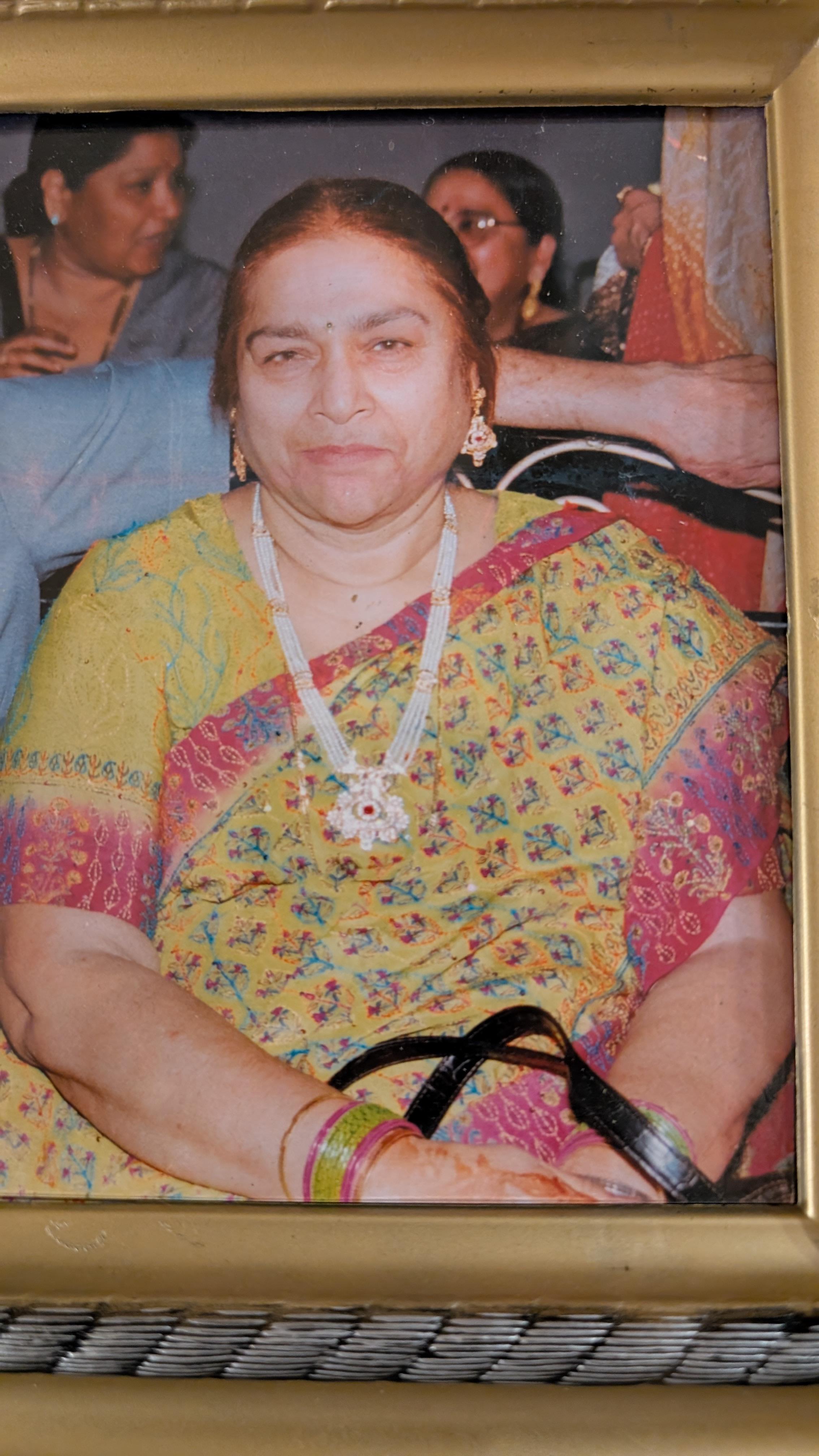 A woman wearing a vibrant sari and jewelry smiles at a festive gathering with friends.