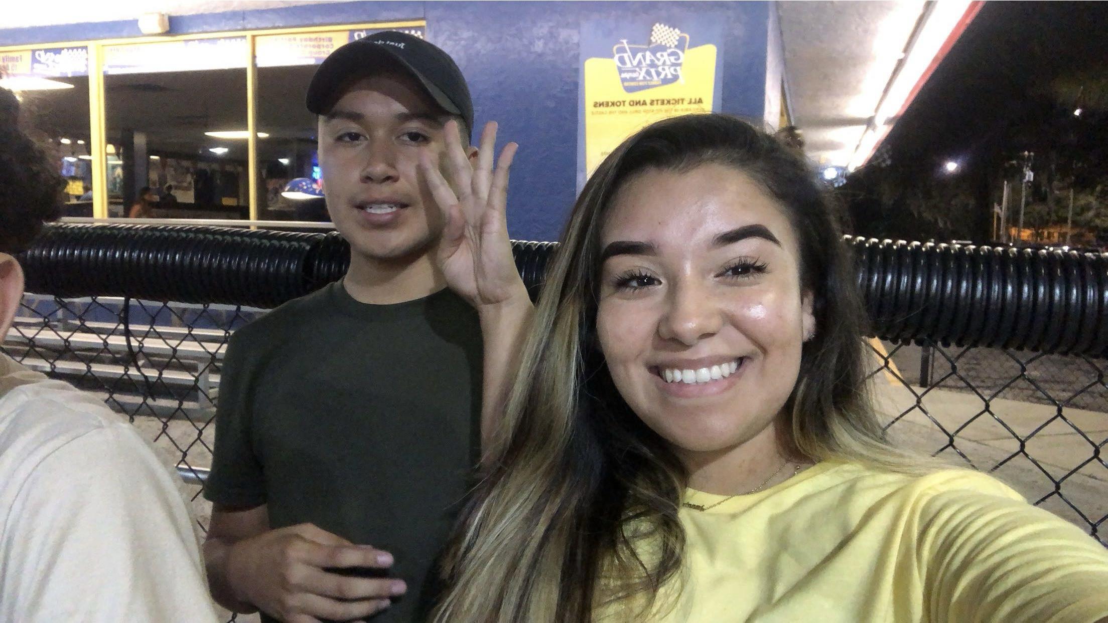 Two friends pose happily together during a lively evening event at a food stand.