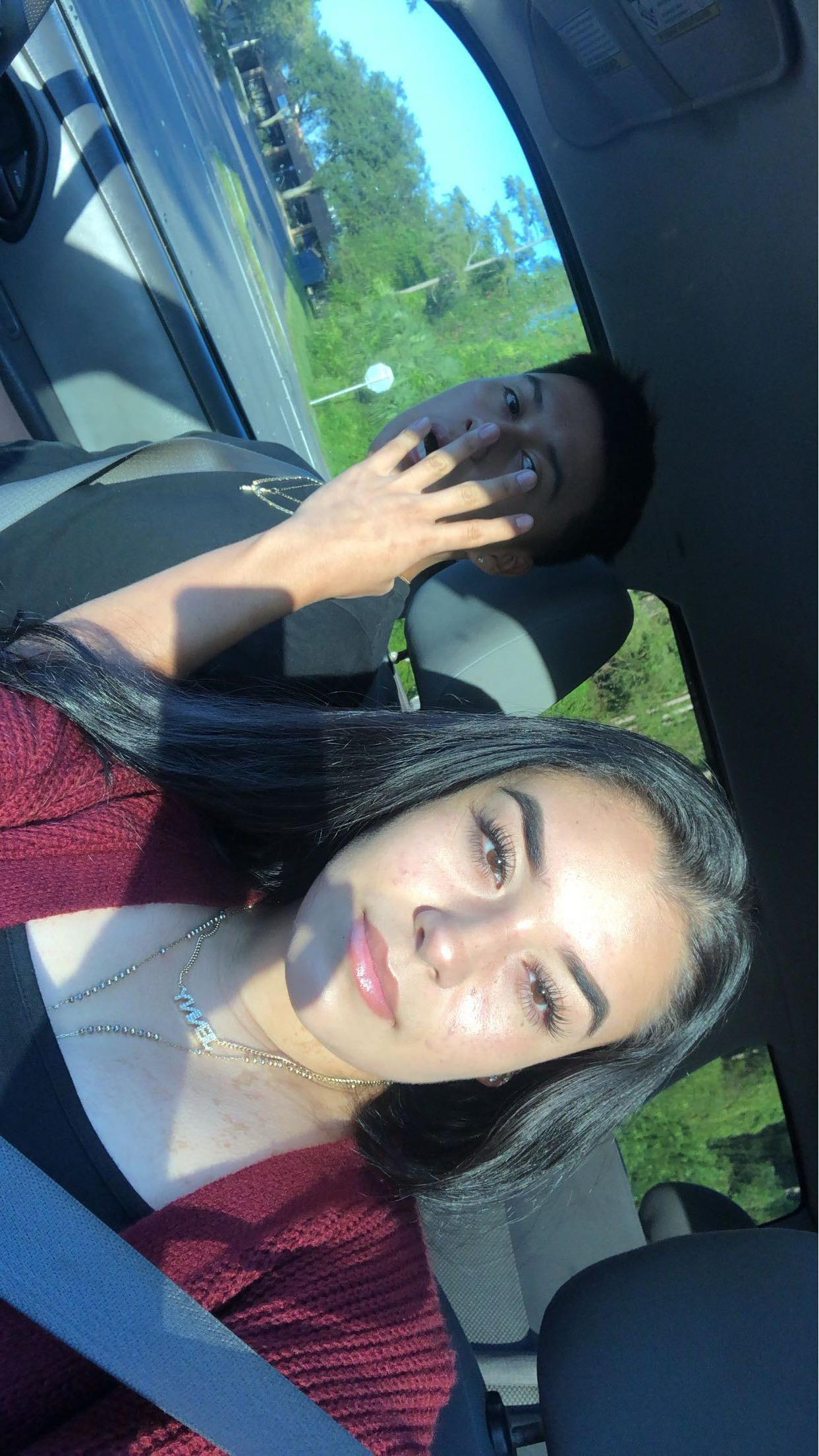 Two people sit in the front seat of a car, smiling and enjoying a sunny drive together.