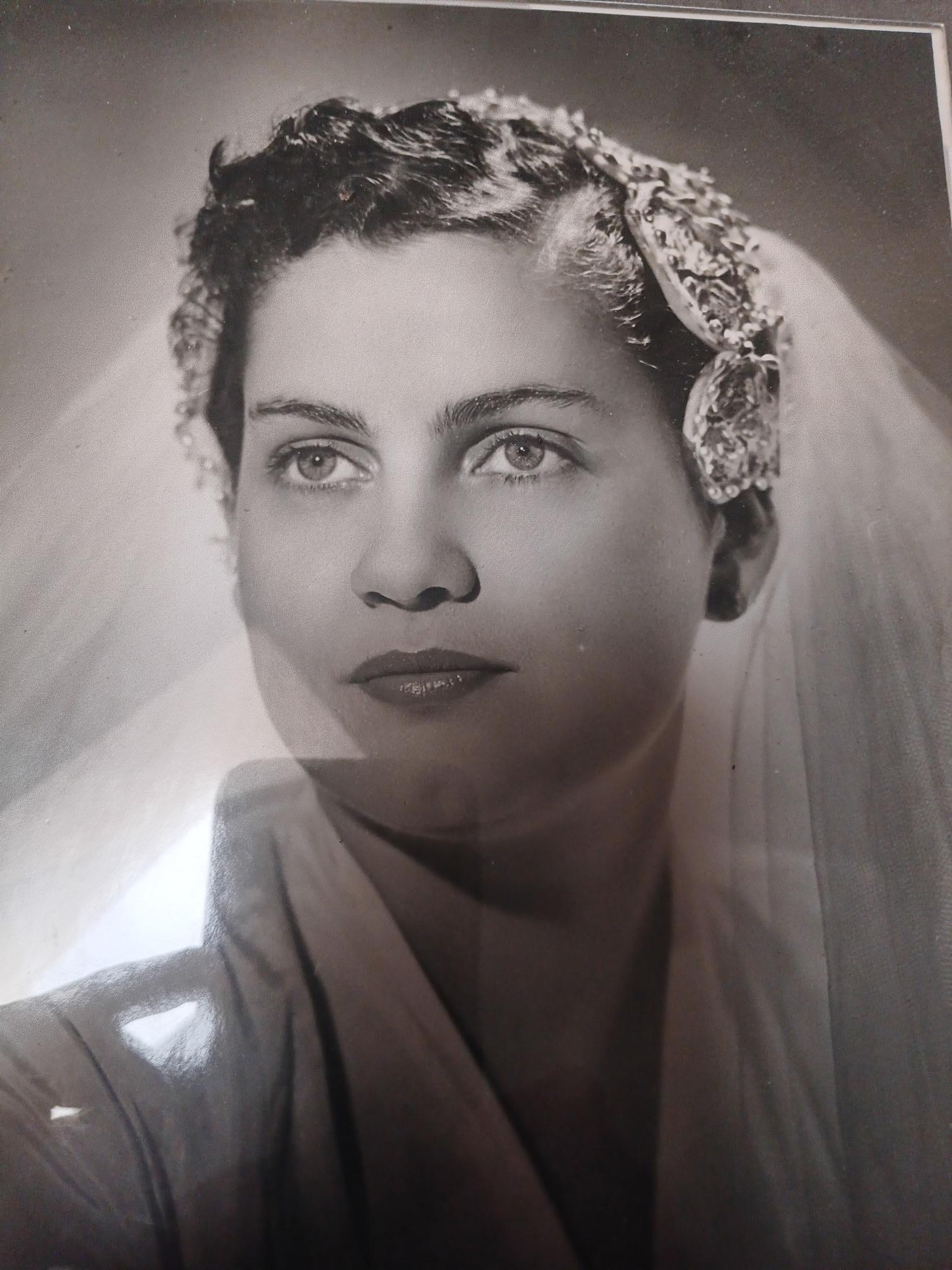 A bride gazes thoughtfully with a serene expression, adorned with a delicate veil and hairpiece.