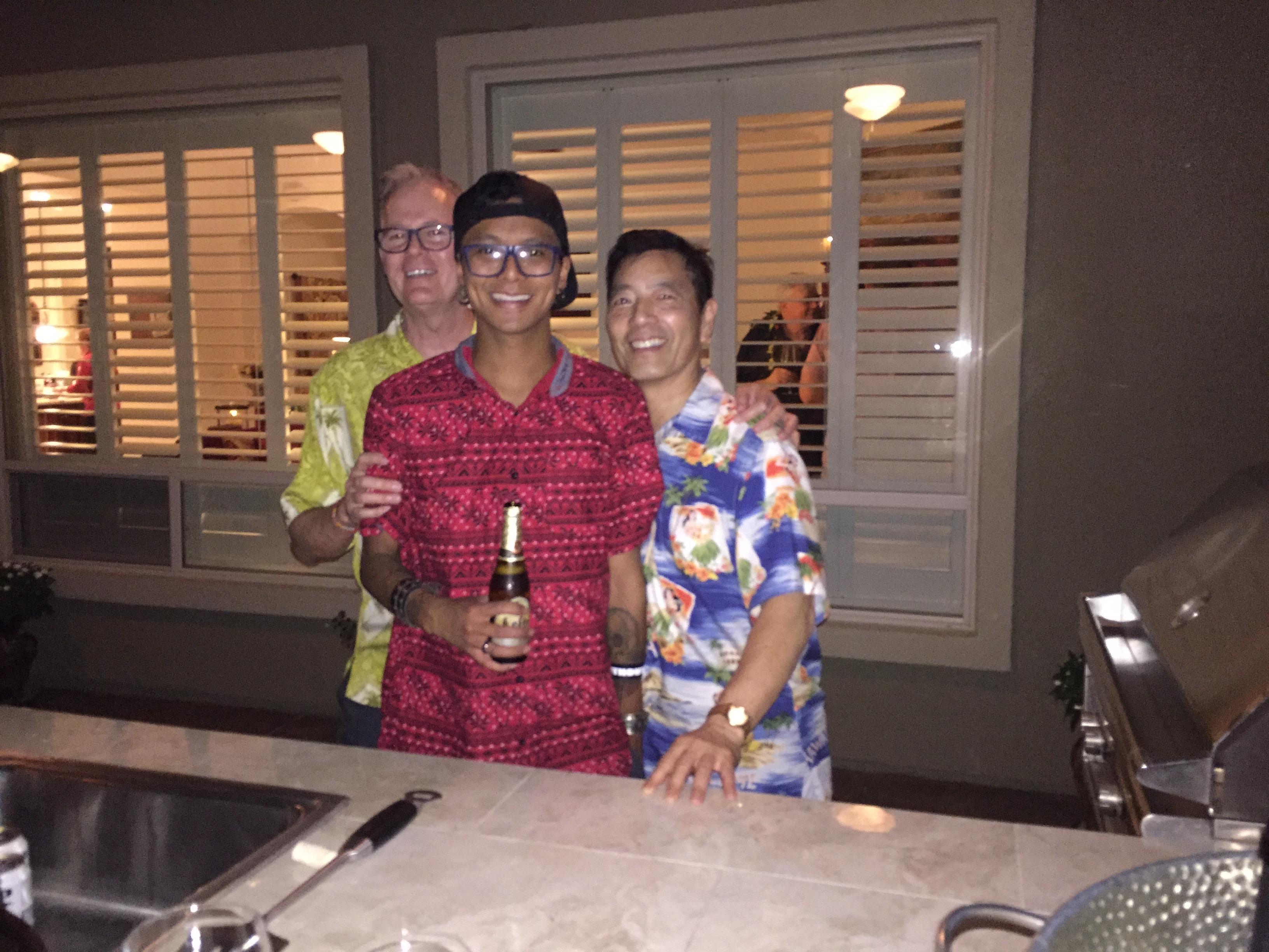 Friends smile and pose together while holding drinks in a well-lit indoor setting.