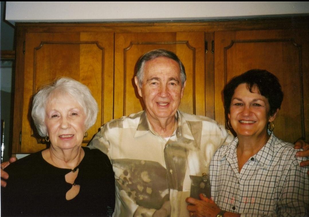 Three adults share happy smiles while posing together in a warm, inviting indoor environment.
