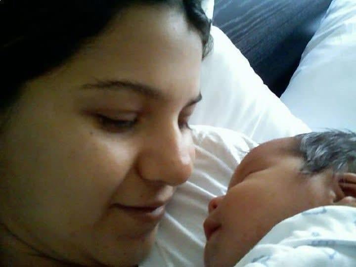 A mother lovingly gazes at her newborn baby in a hospital bed, creating a tender moment.