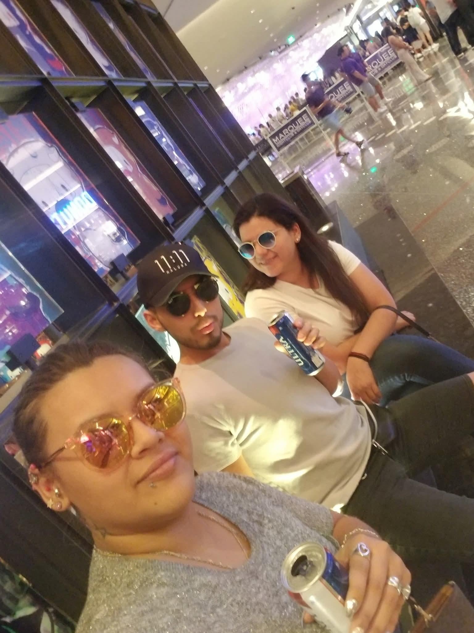 Friends relax and chat while sitting in a busy shopping center in the evening.