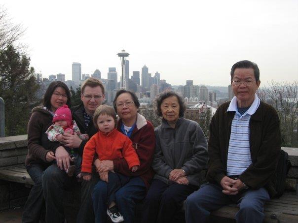 A group of people sits together at a viewpoint overlooking Seattle's skyline with the Space Needle.