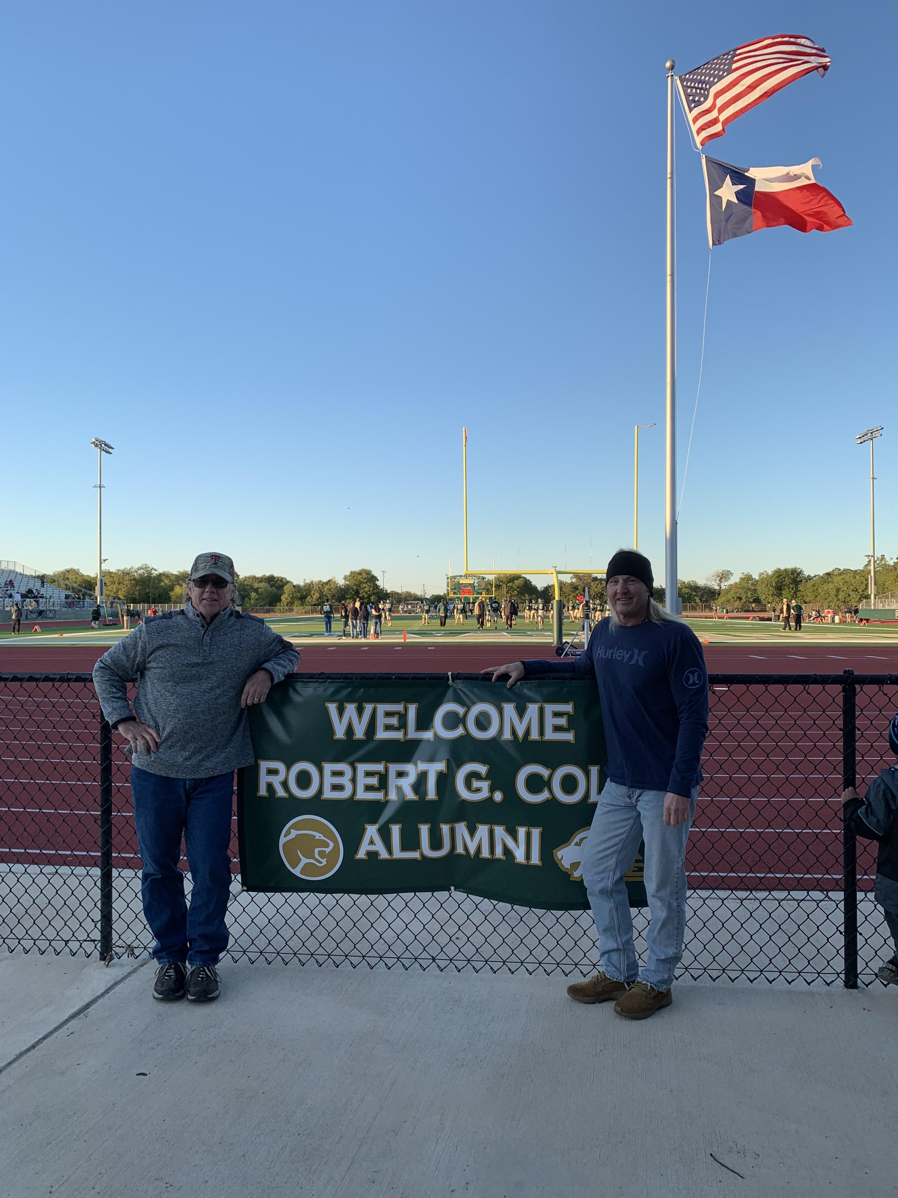 Alumni stand by a sign welcoming visitors to Robert G.