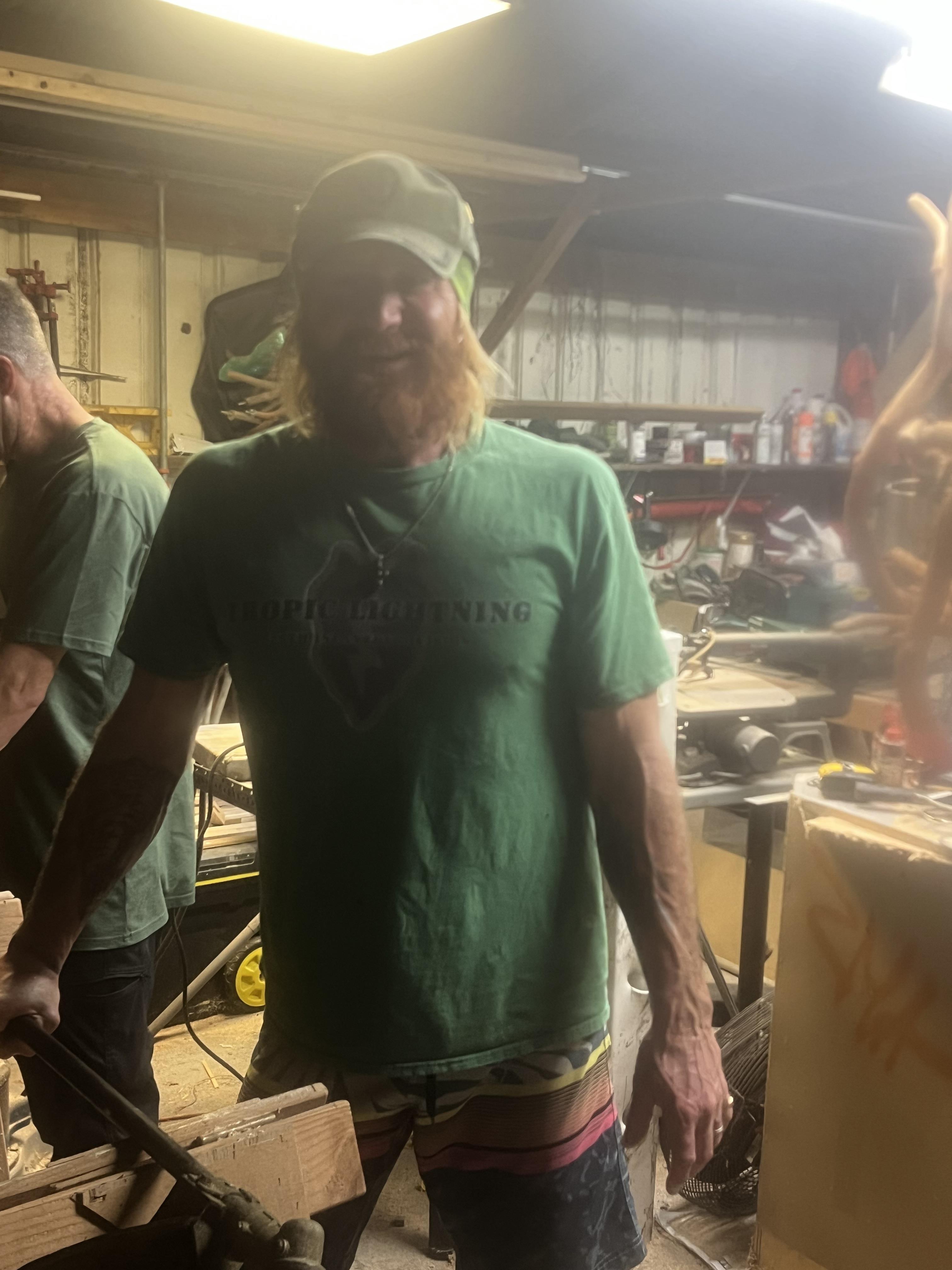 A skilled craftsman works on a wooden sculpture in a workshop filled with tools and other creations.