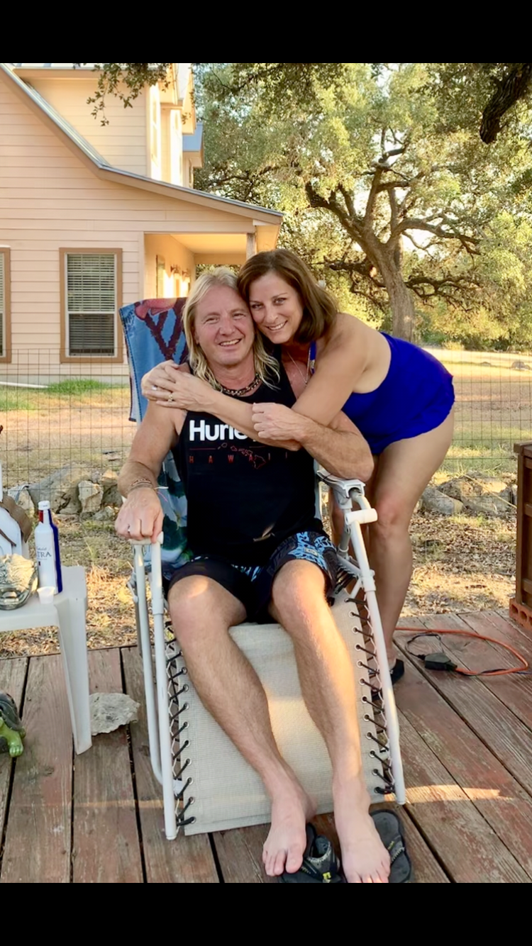 Two people share a warm embrace while sitting outdoors in a cozy backyard setting.