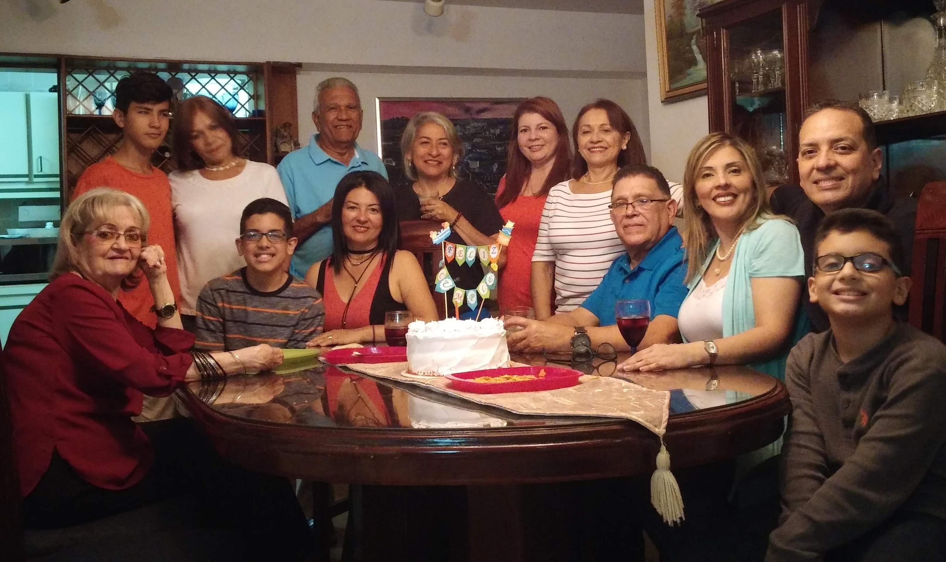 A joyful family gathering around a table with a cake, celebrating together in a cozy setting.