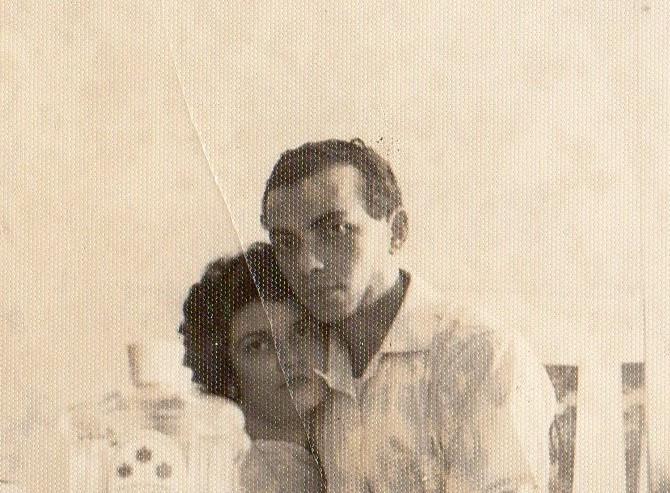A couple embraces in a soft-lit room, expressing love and warmth through their poses.