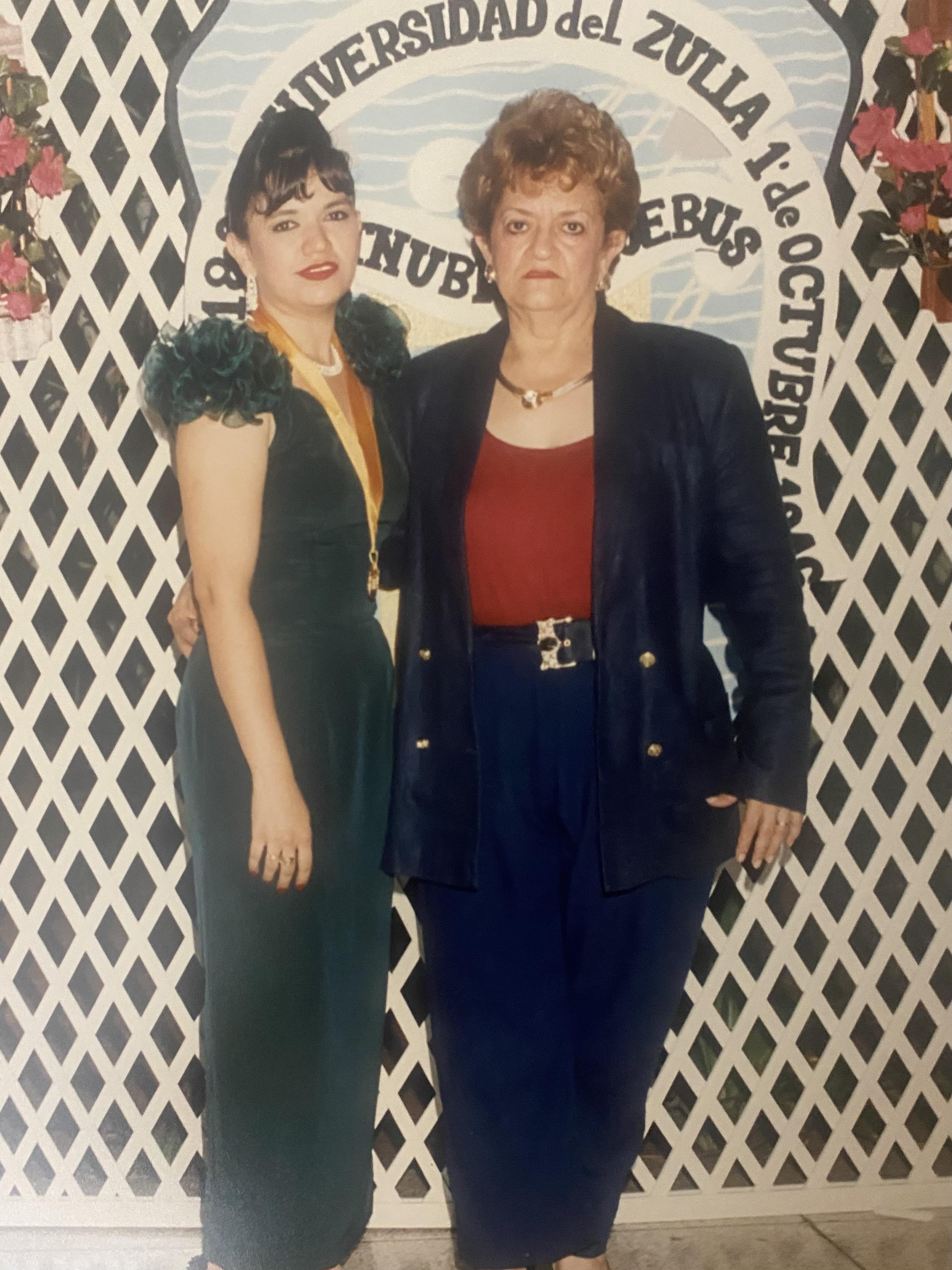 Two women stand together, smiling at a festive event with vibrant decorations.