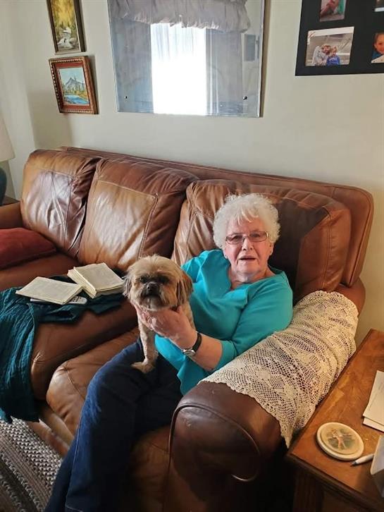 A woman sitting on a couch holding a dog