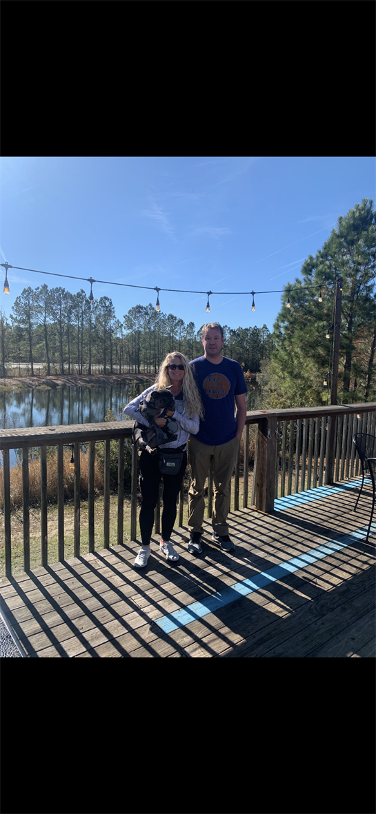 A man and woman standing on a deck with a dog
