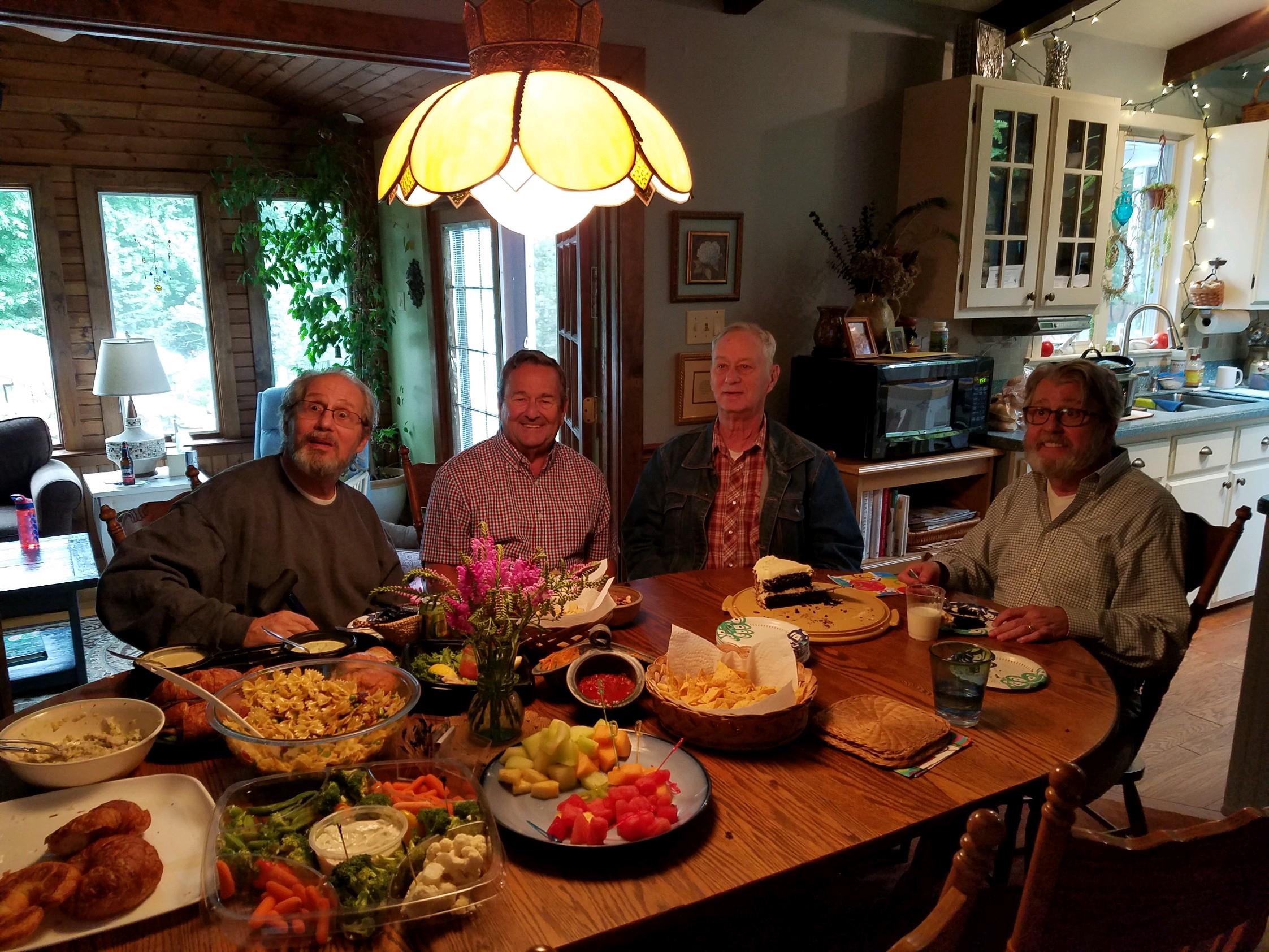A group of friends enjoys a lively meal together at a well-set dining table filled with dishes.