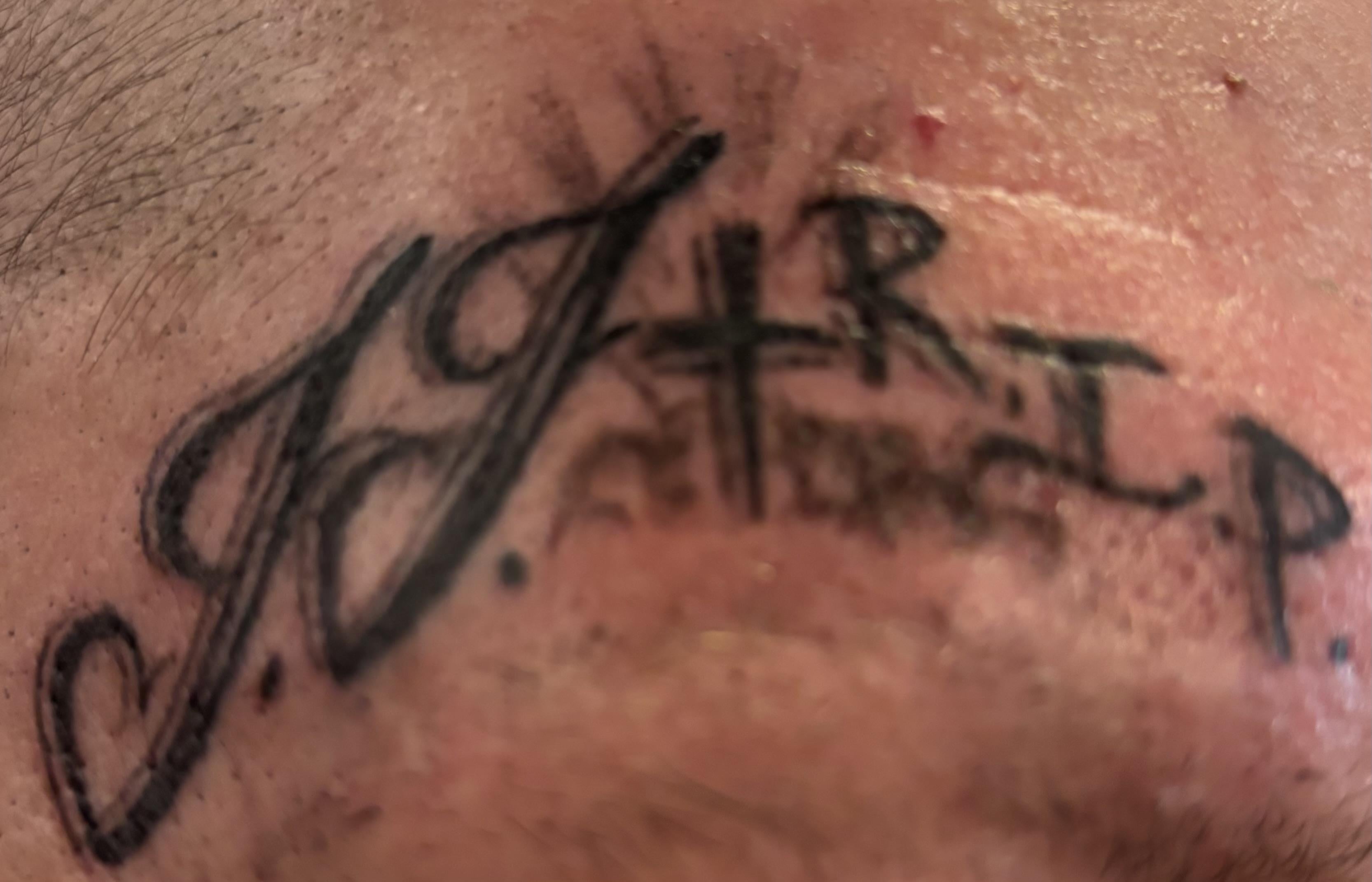 Close-up of an intricate tattoo on skin showcasing bold lettering and creative design elements.