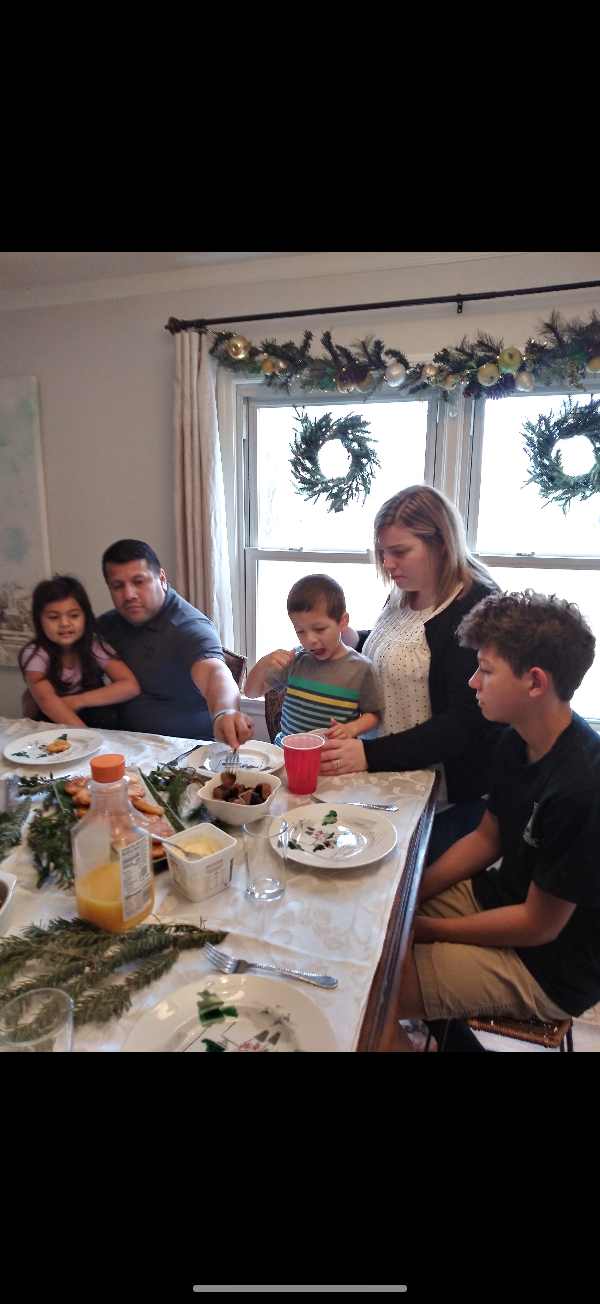 A family shares a meal at the dining table, enjoying each other's company in winter.