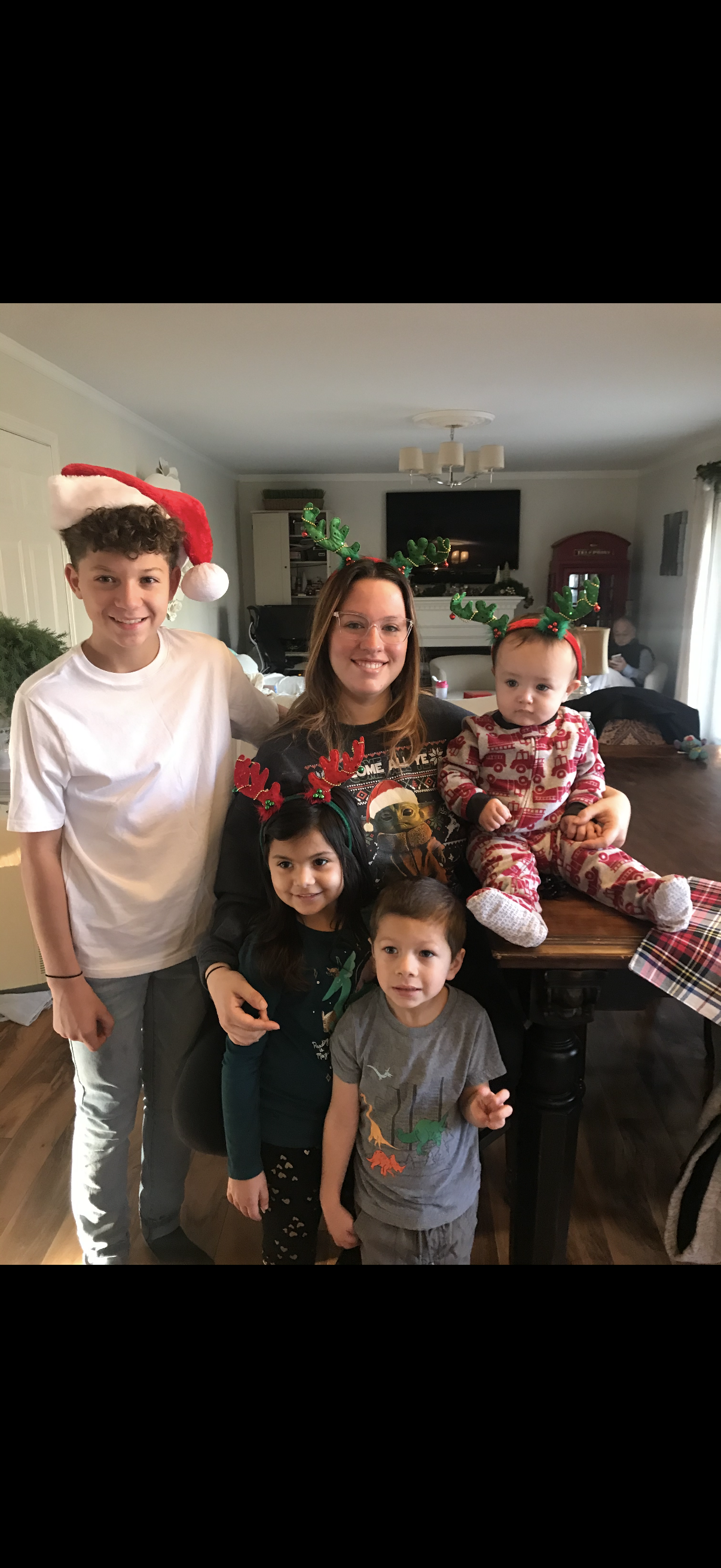 A family gathers together wearing holiday hats, celebrating the festive season indoors.