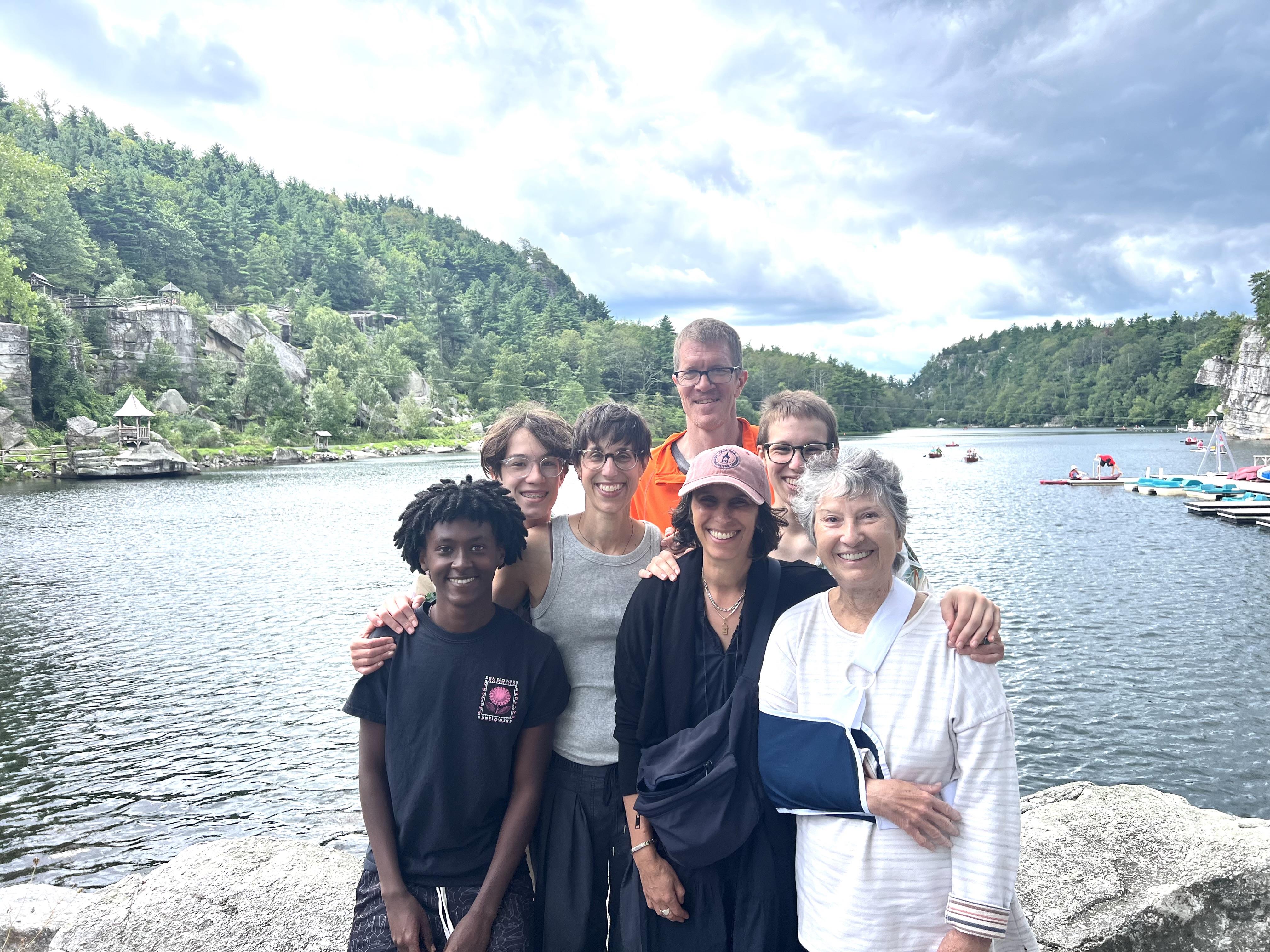 Friends gather by the lake, smiling and enjoying a sunny day surrounded by nature.