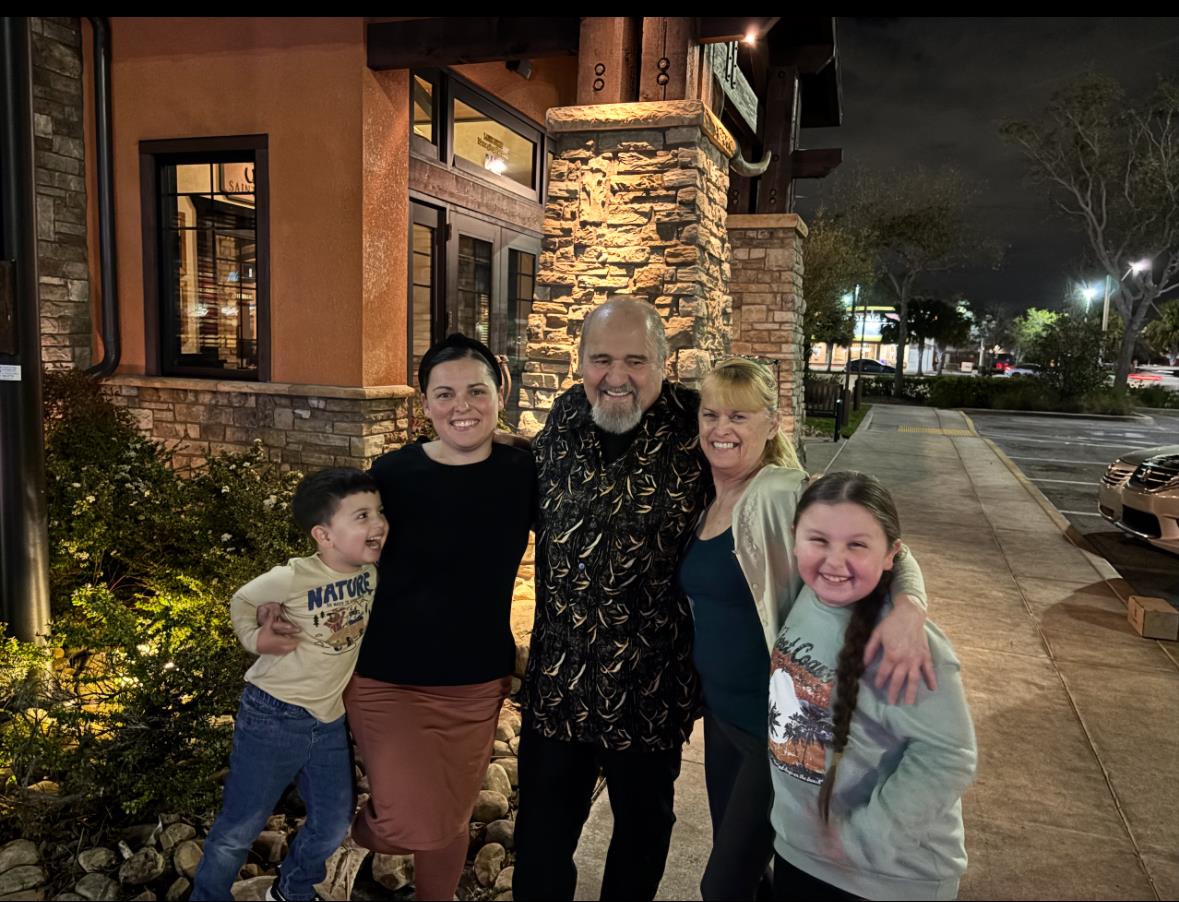 A group of five friends enjoys a lively evening outside a restaurant, sharing joy and togetherness.