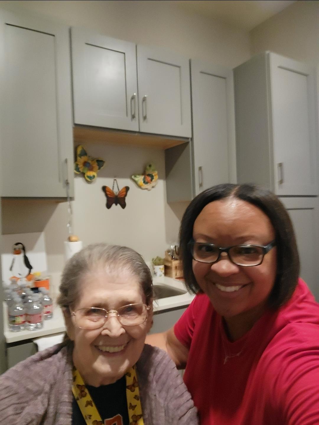 Two women enjoy a happy time together in a warm kitchen, smiling at the camera.