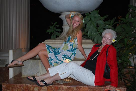 A woman and a young woman sitting on a stone ledge