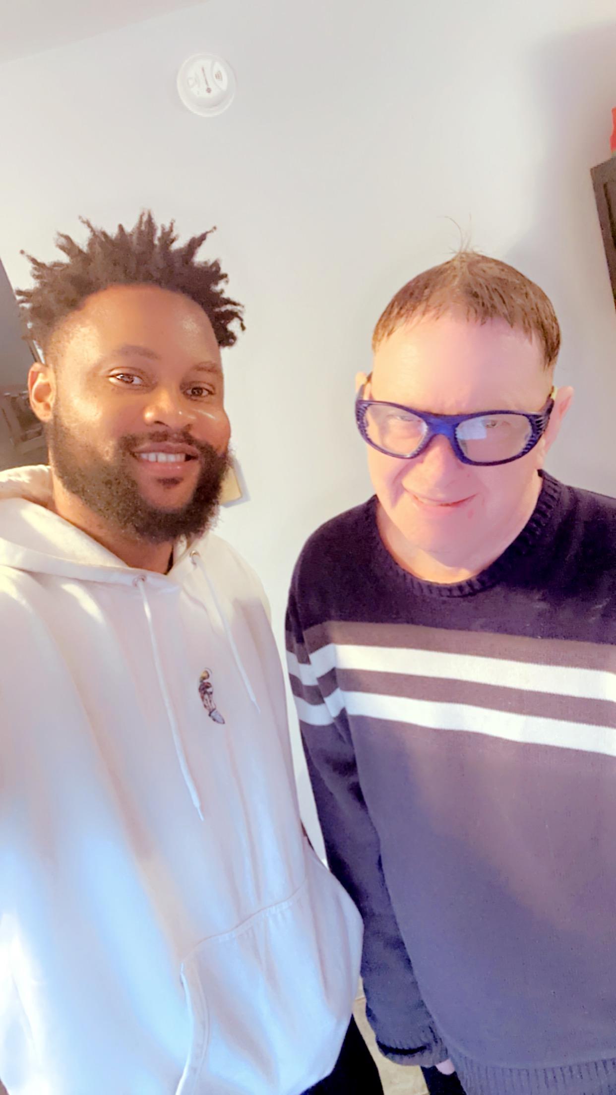 Two friends share a joyful moment, smiling together in a cozy indoor setting with natural light.