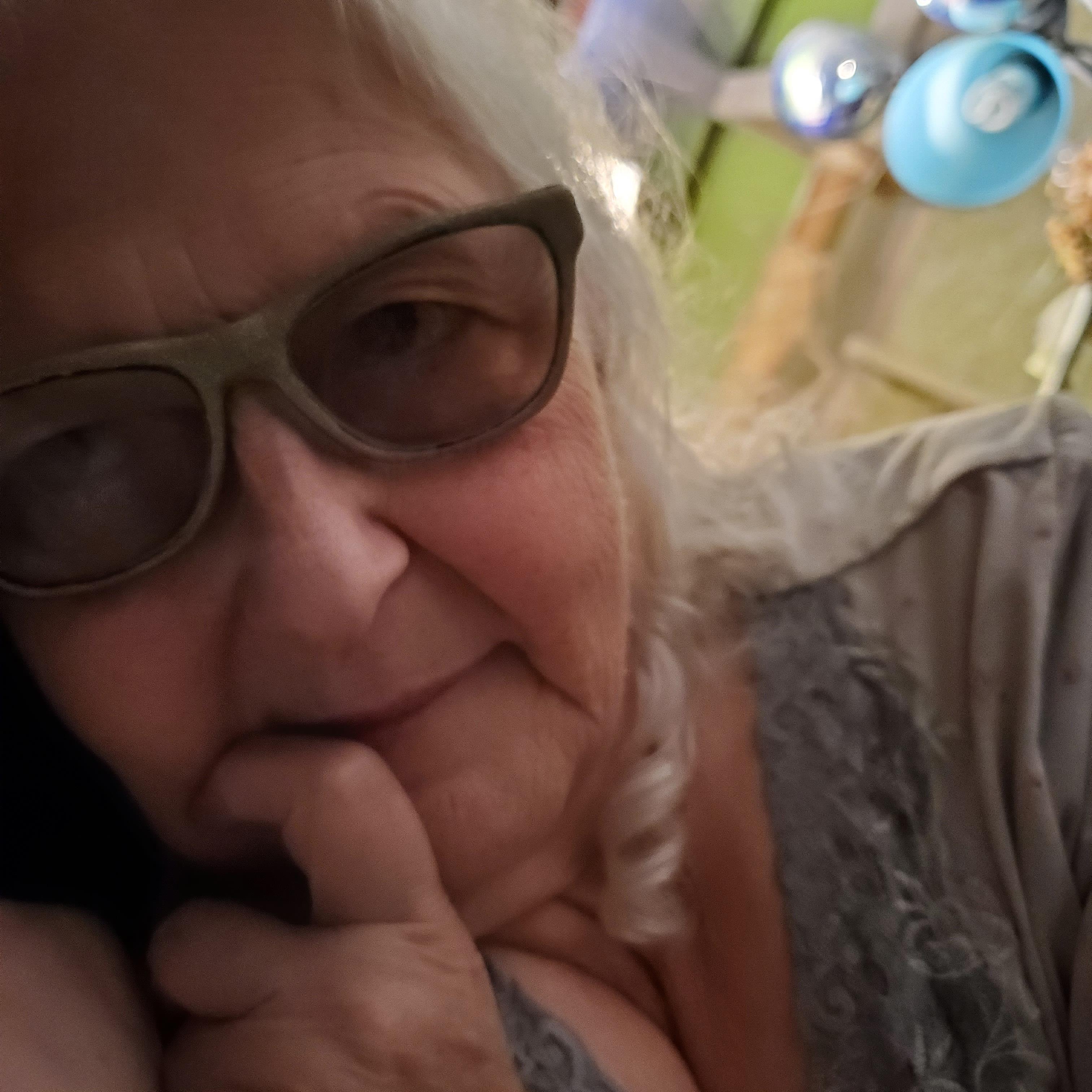Close-up of an elderly woman with gray hair smiling and enjoying her day indoors.