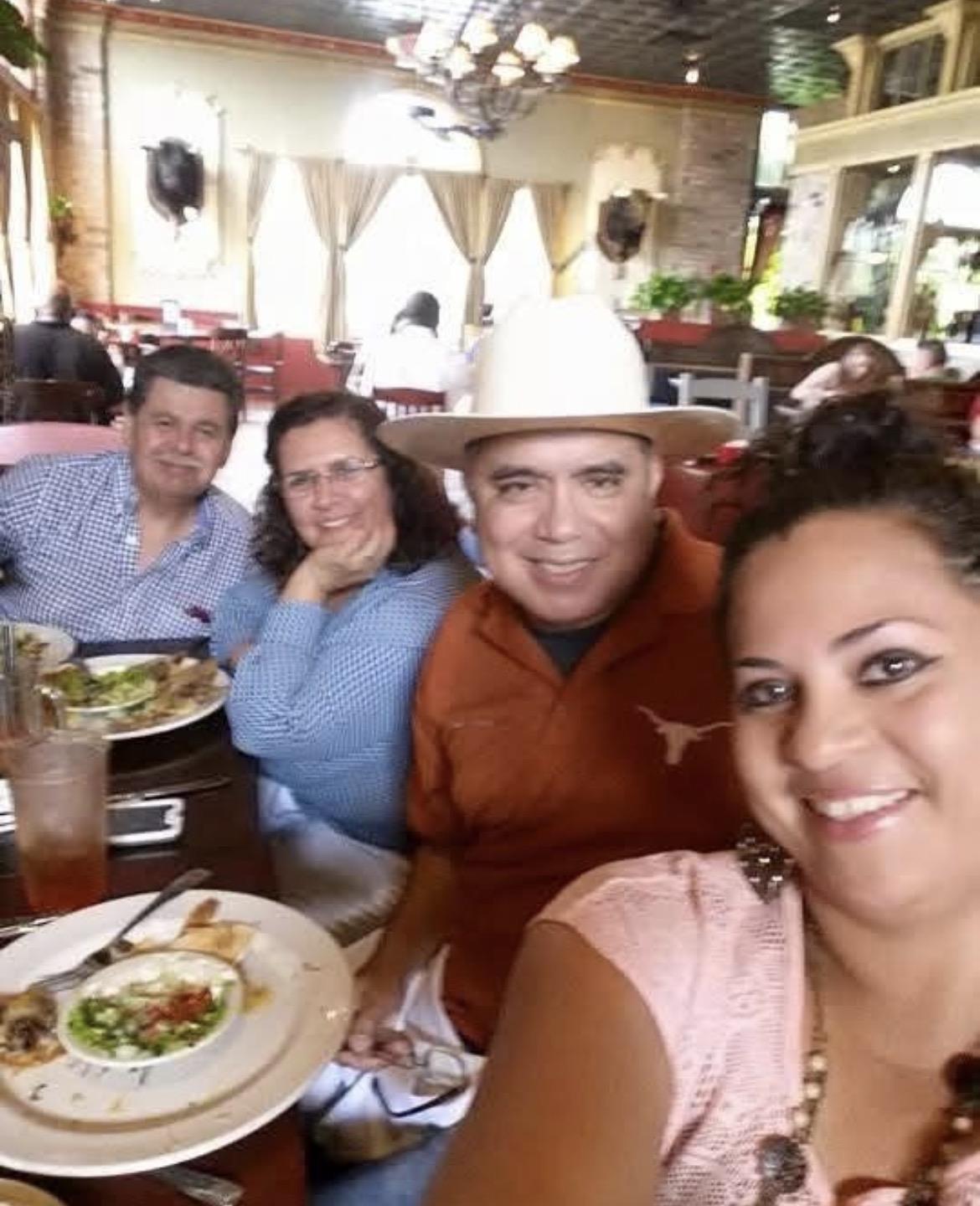 Group of friends smiling and sharing a meal at a bustling restaurant during lunchtime.