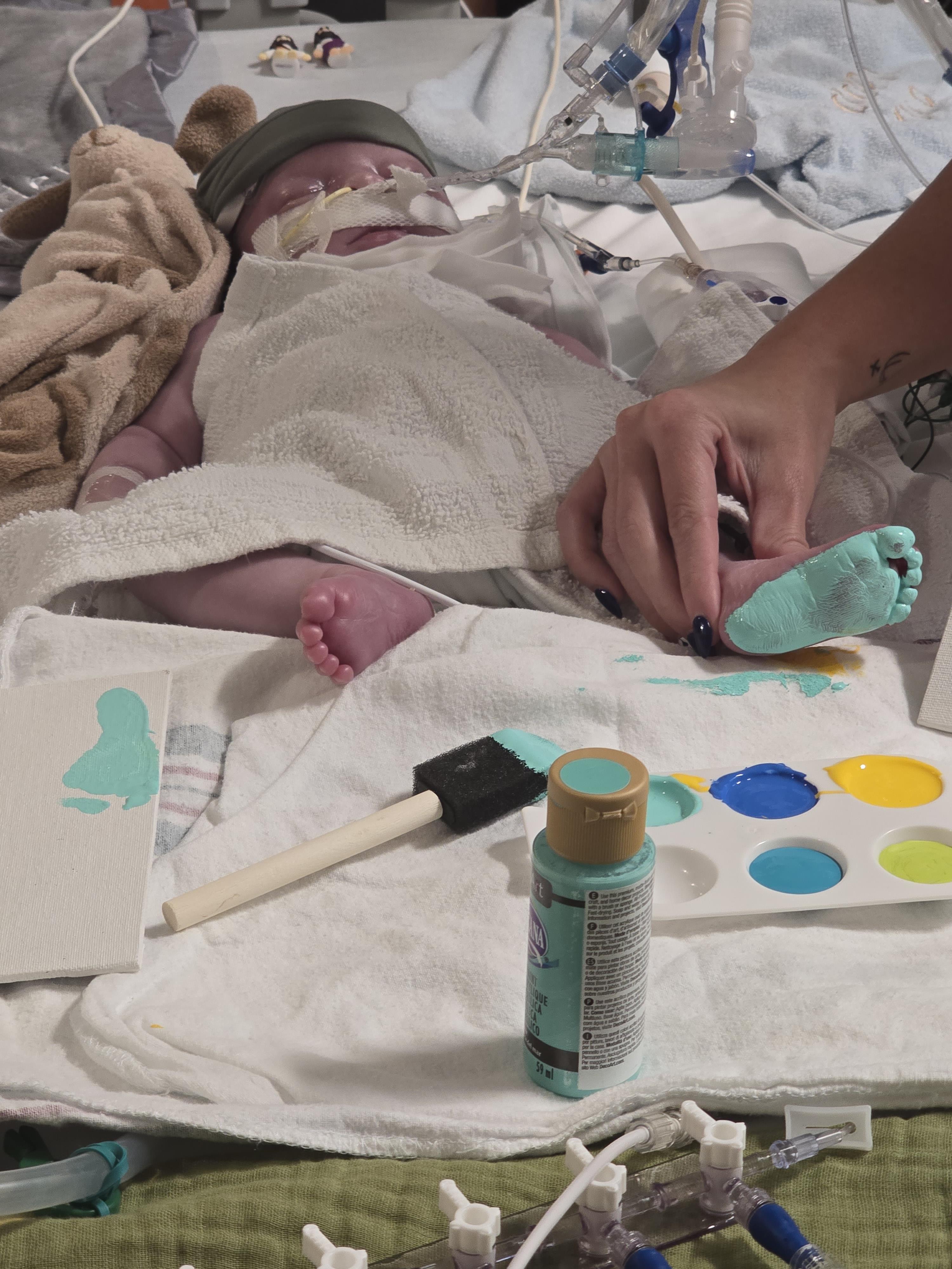 A parent engages in fun art activity with a baby, using paint to make colorful handprints.