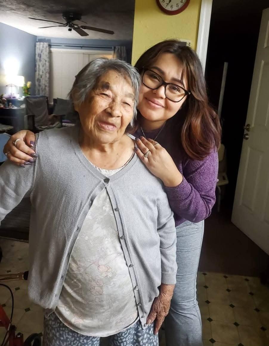 A loving grandmother poses with her granddaughter in a relaxed home environment, smiling happily.