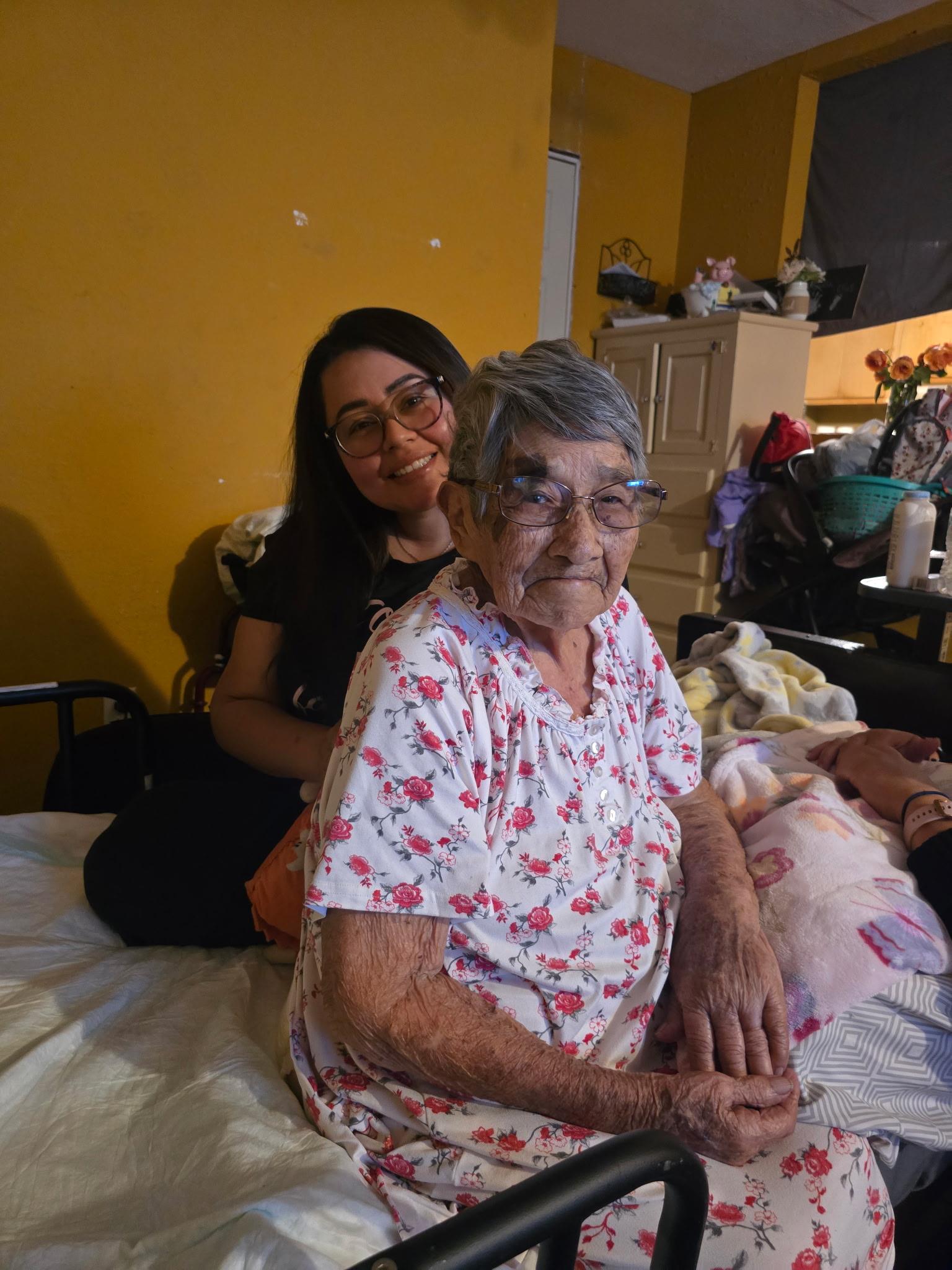 Grandmother and granddaughter enjoy each other's company on a bed filled with memories and warmth.