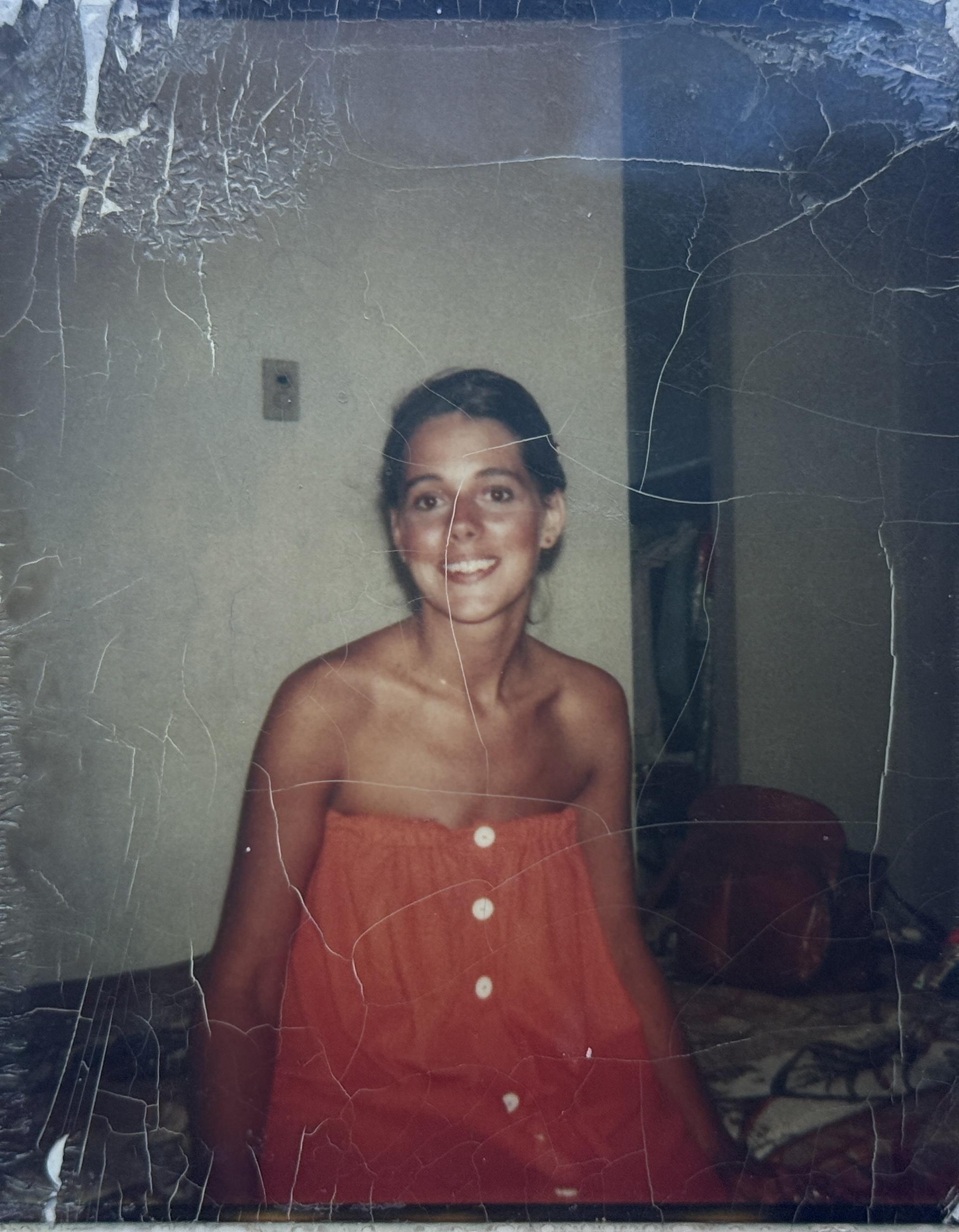 Young woman wearing a red dress smiles happily in a bright, inviting room.