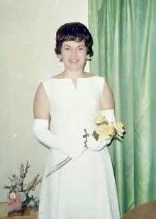 Woman stands with a bouquet of flowers in her hands at an event in the 1960s.