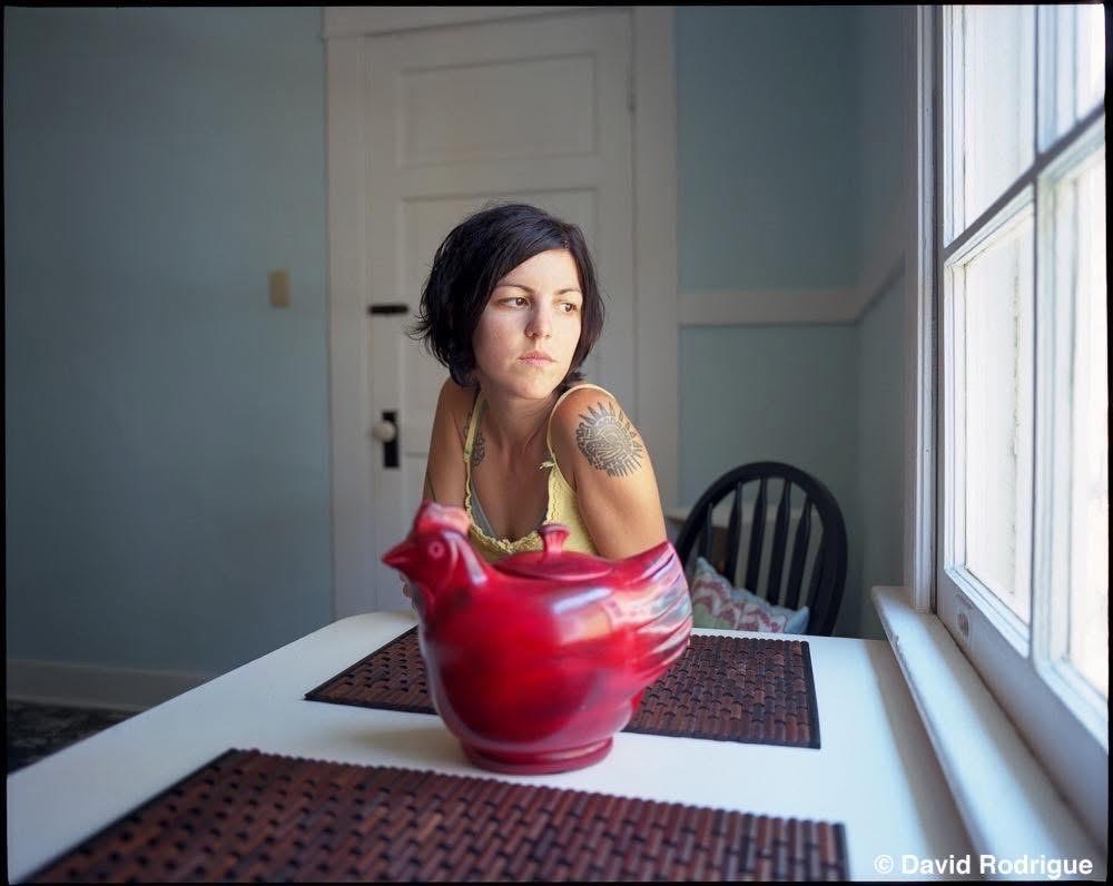 A woman sitting at a table with a red ceramic chicken
