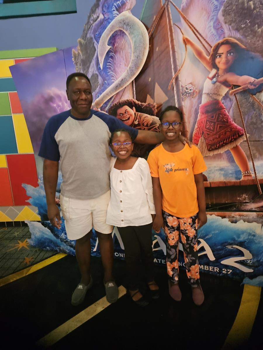 A father and two children stand together at a movie theater before watching a film.