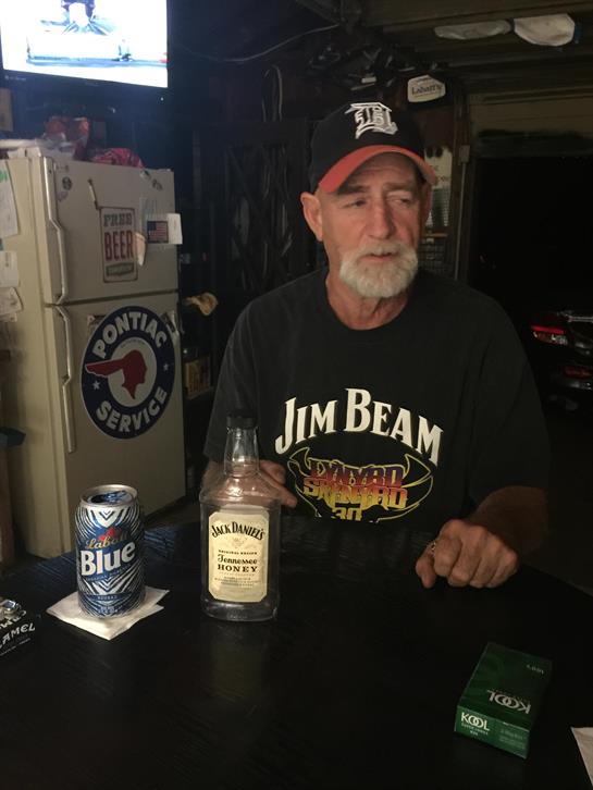 A man sitting at a table with a bottle of honey and a can of beer