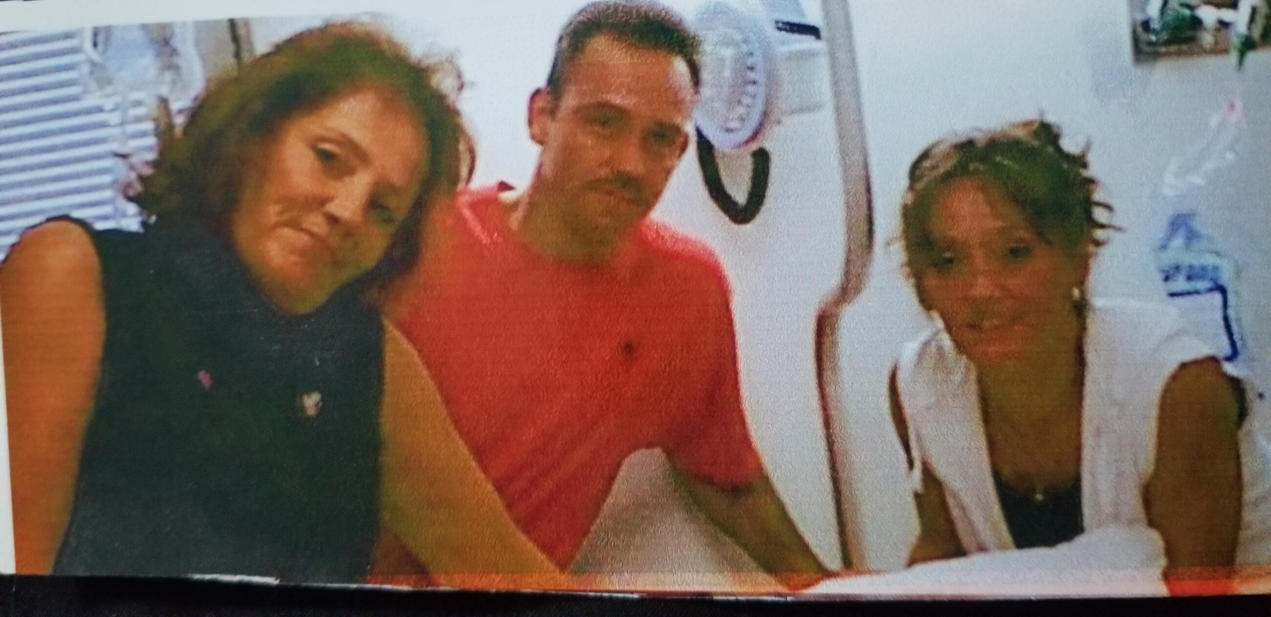 A group of three people poses together for a picture in a small, bright space.